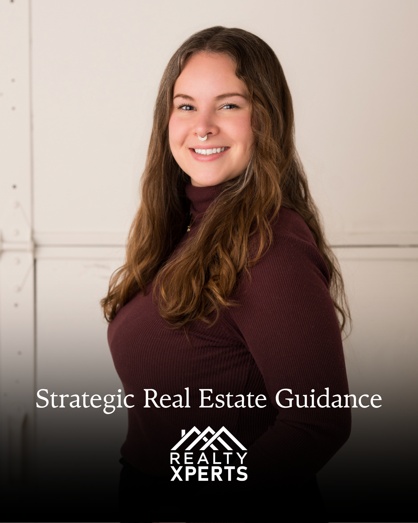 A Fargo Moorhead Realtor smiling with brown hair, wearing a maroon turtleneck, standing in front of a plain white wall, with overlay text that reads 'Strategic Real Estate Guidance' and 'REALT XPERTS' logo at the bottom.
