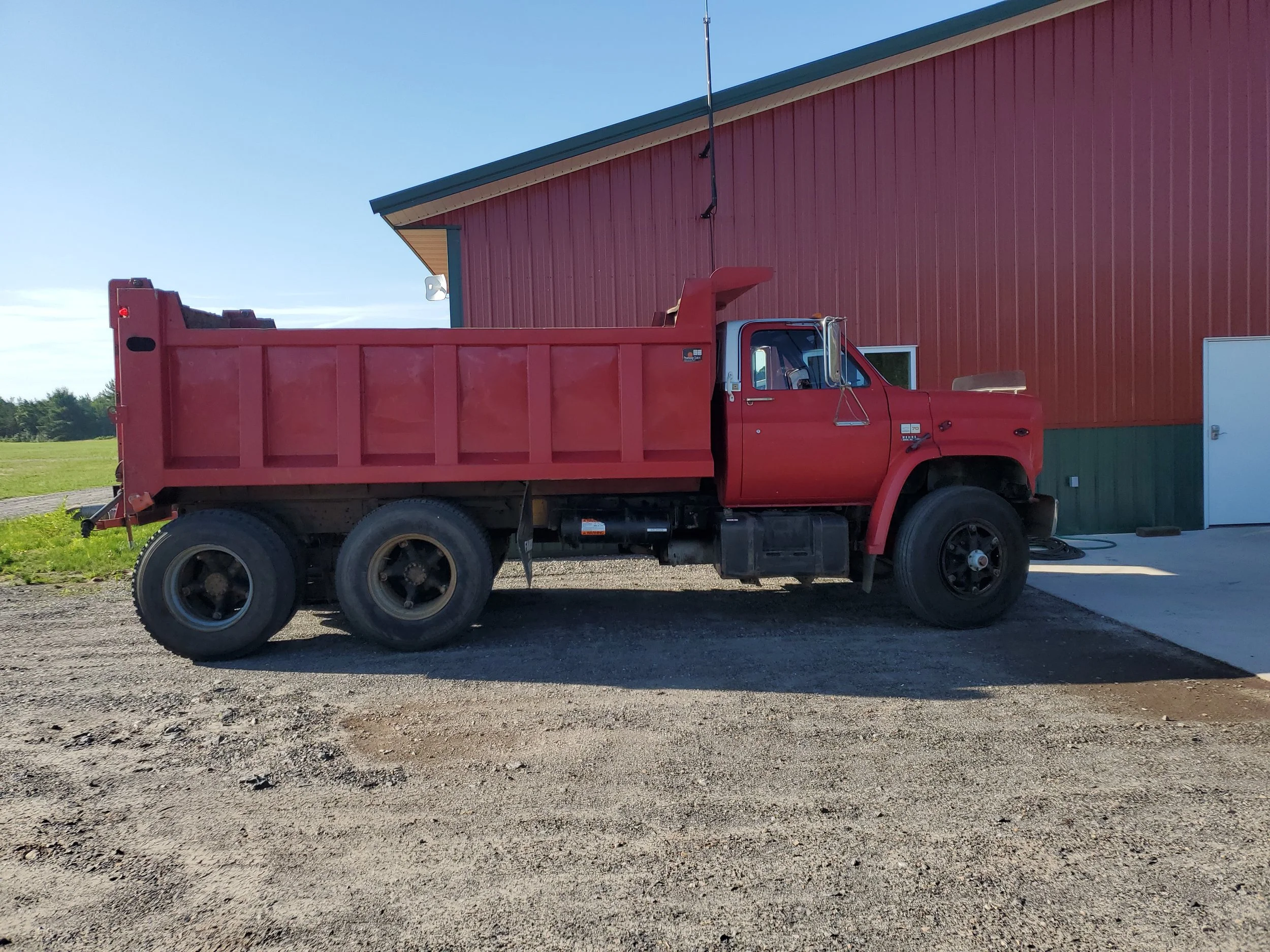 Red dump truck next to shop