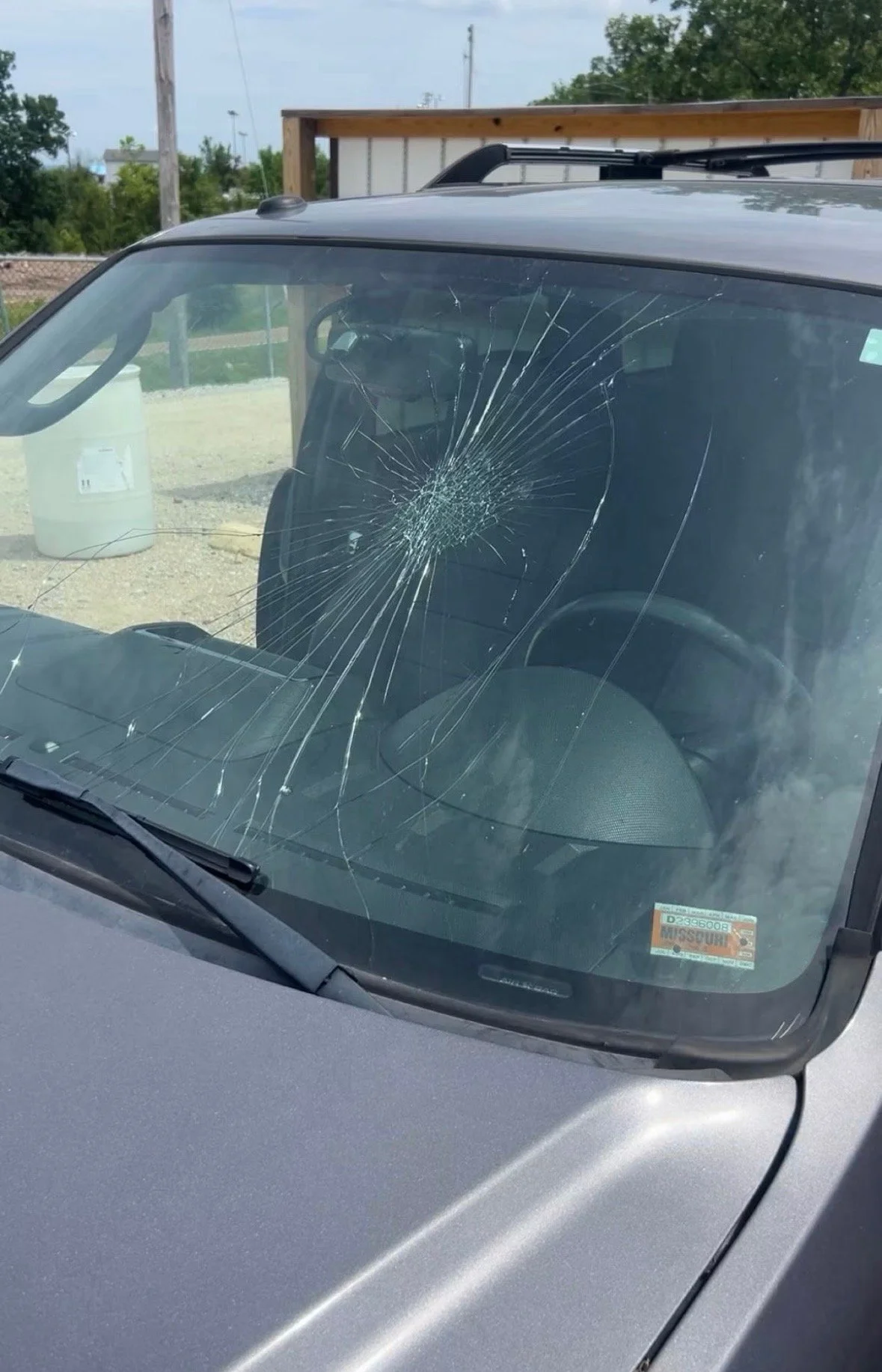 A vehicle with a cracked windshield, showing a spider web pattern of damage on the glass.