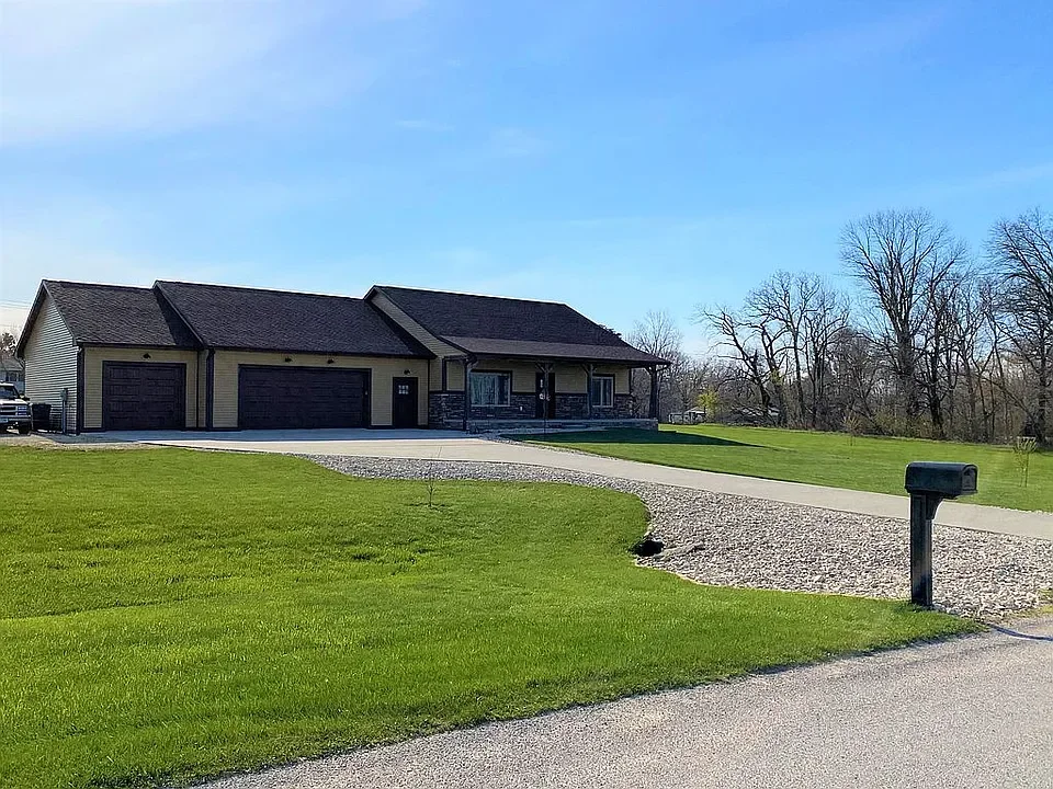 A suburban house with three garage doors, a driveway, a mailbox, and a well-maintained lawn.