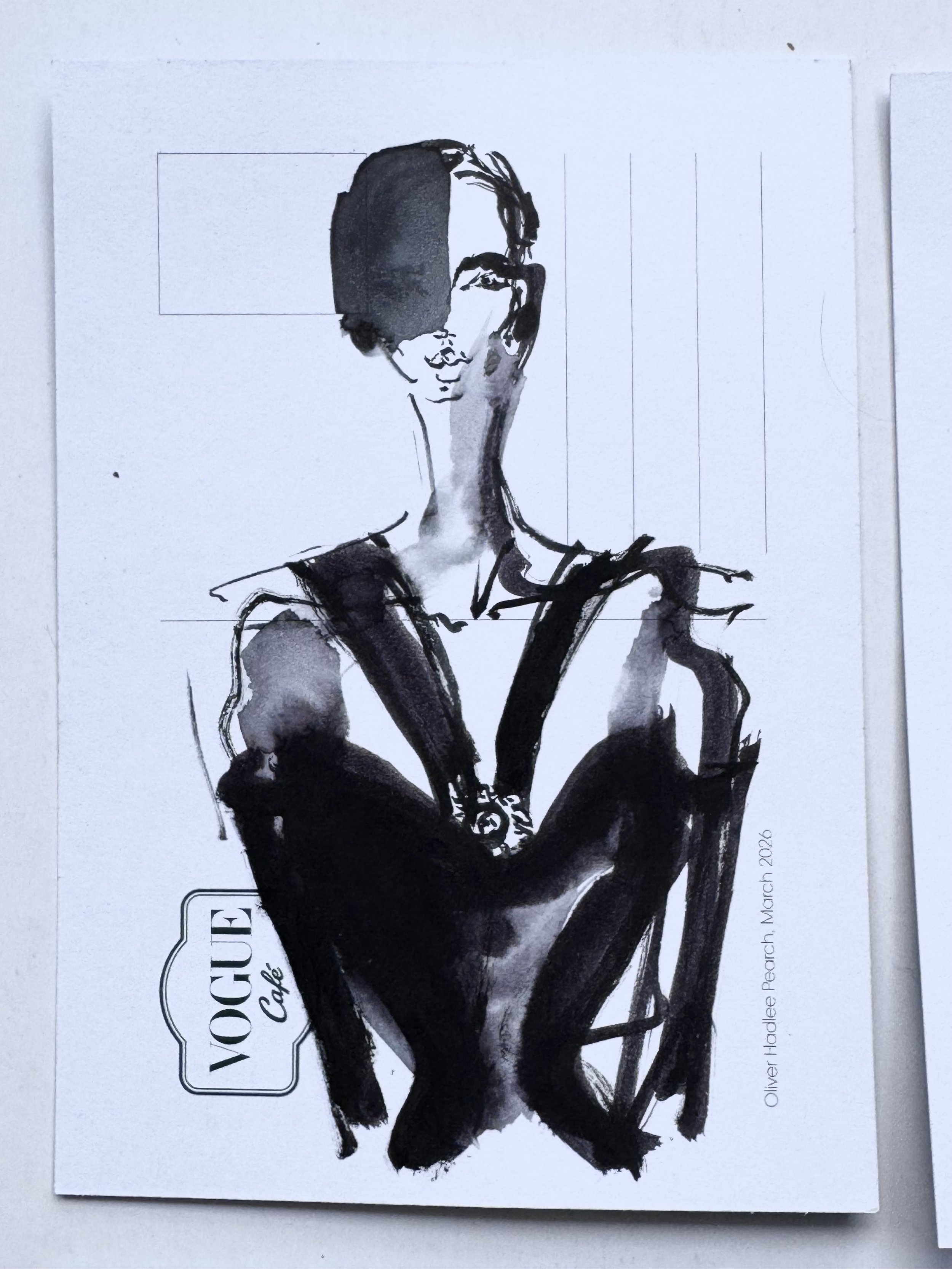 Black ink watercolor painting of a woman with short hair, wearing glasses, and a dark top, sitting with her arms crossed. The artwork is on a white background with a label reading "Woodley Cafe" and includes the artist's signature "Oliver Holden Peach March 2020."