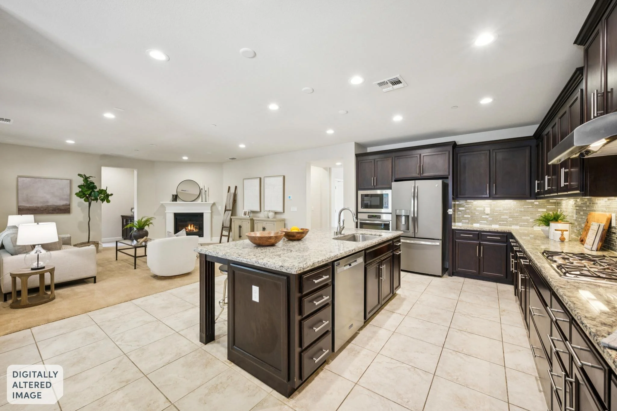 Open-concept modern kitchen with dark wood cabinets, granite countertops, a kitchen island, and stainless steel appliances, adjoining a living area with a fireplace and seating.