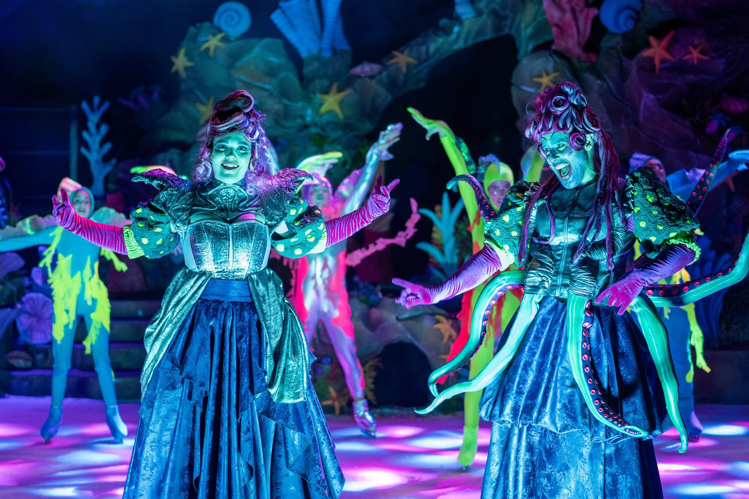 Cena de conjunto de "A Pequena Sereia No Gelo" com personagens do universo marinho, figurinos inspirados no oceano e uma iluminação cénica vibrante que destaca a riqueza do mundo submarino.
