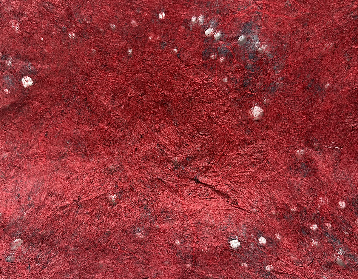 Close-up of textured red Joomchi paper with small felted holes