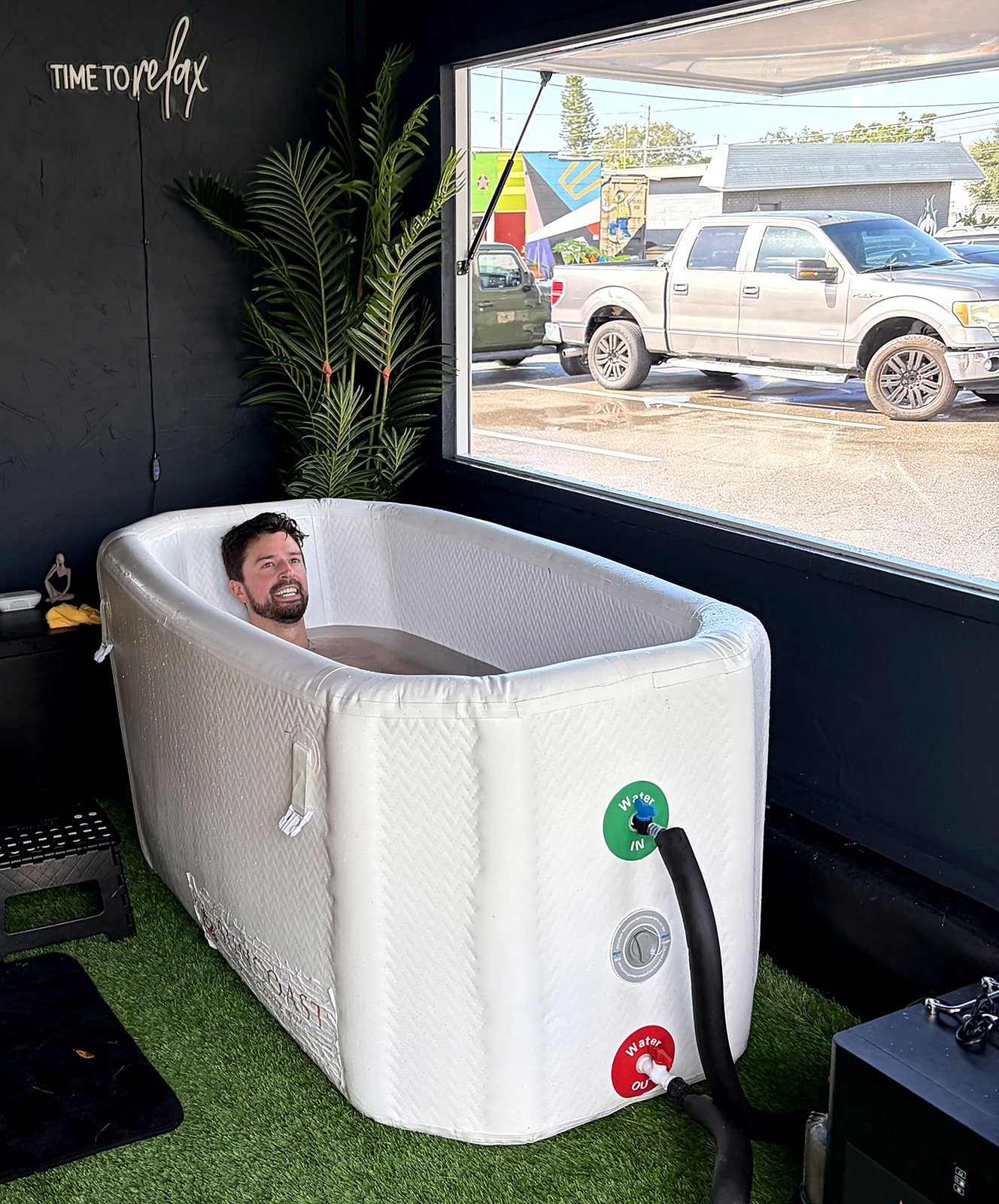 Guest smiling in the cold plunge inside the Suncoast Recovery mobile trailer in Tampa Bay