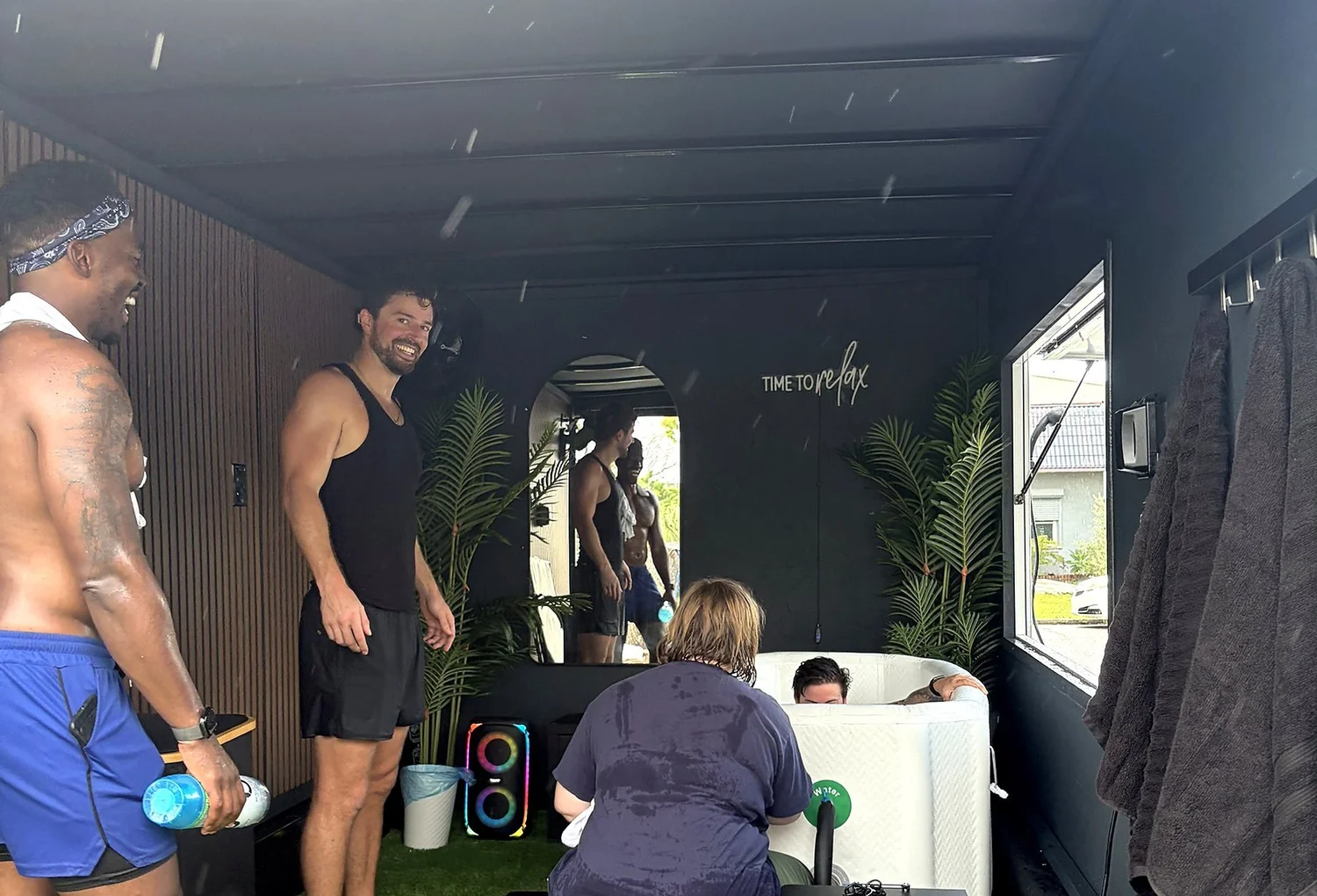 Run club members laughing at the Suncoast Recovery cold plunge trailer at a community event in Tampa
