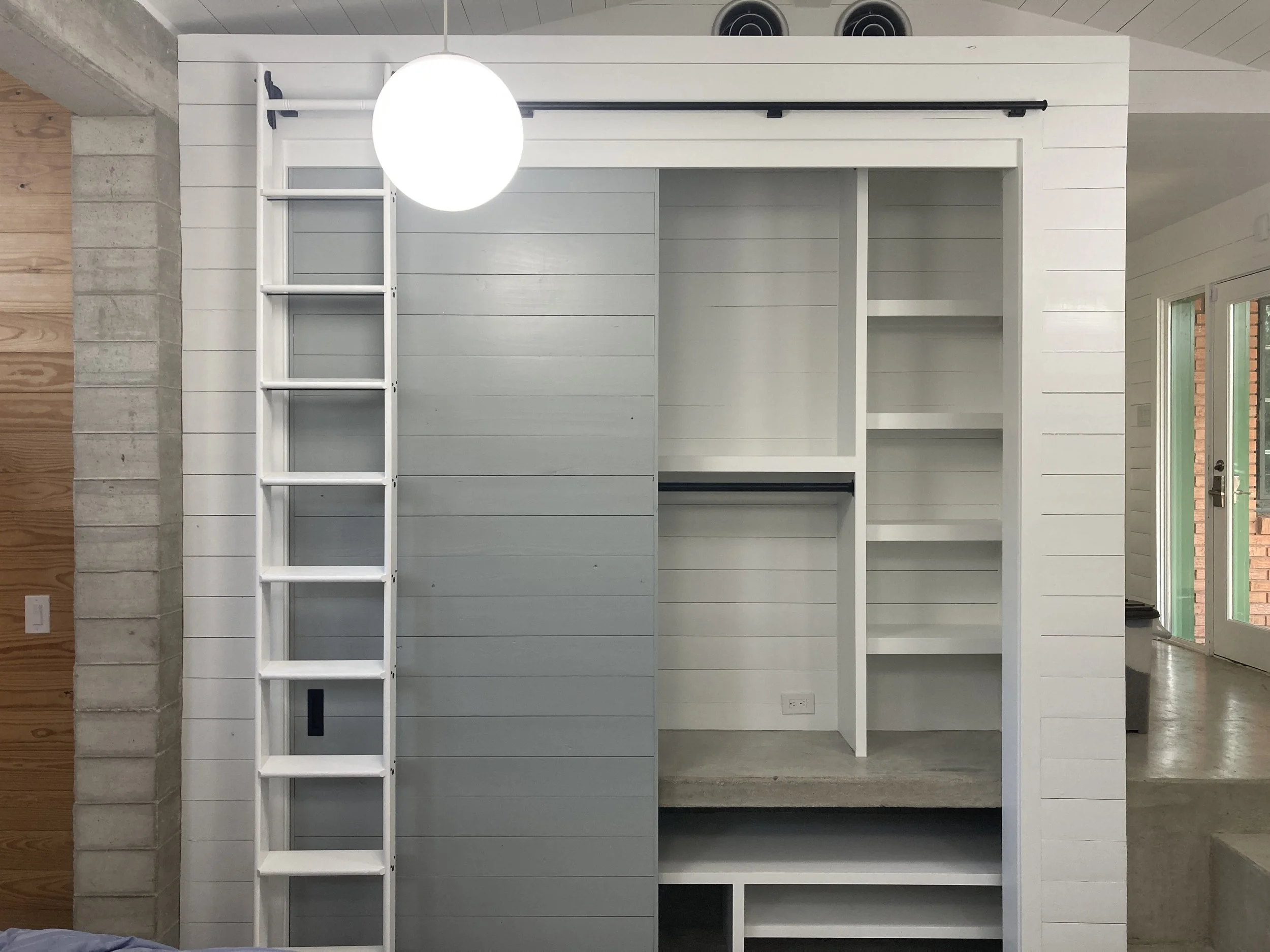 Built-in shelving unit and a small ladder against a wall in a modern interior space.
