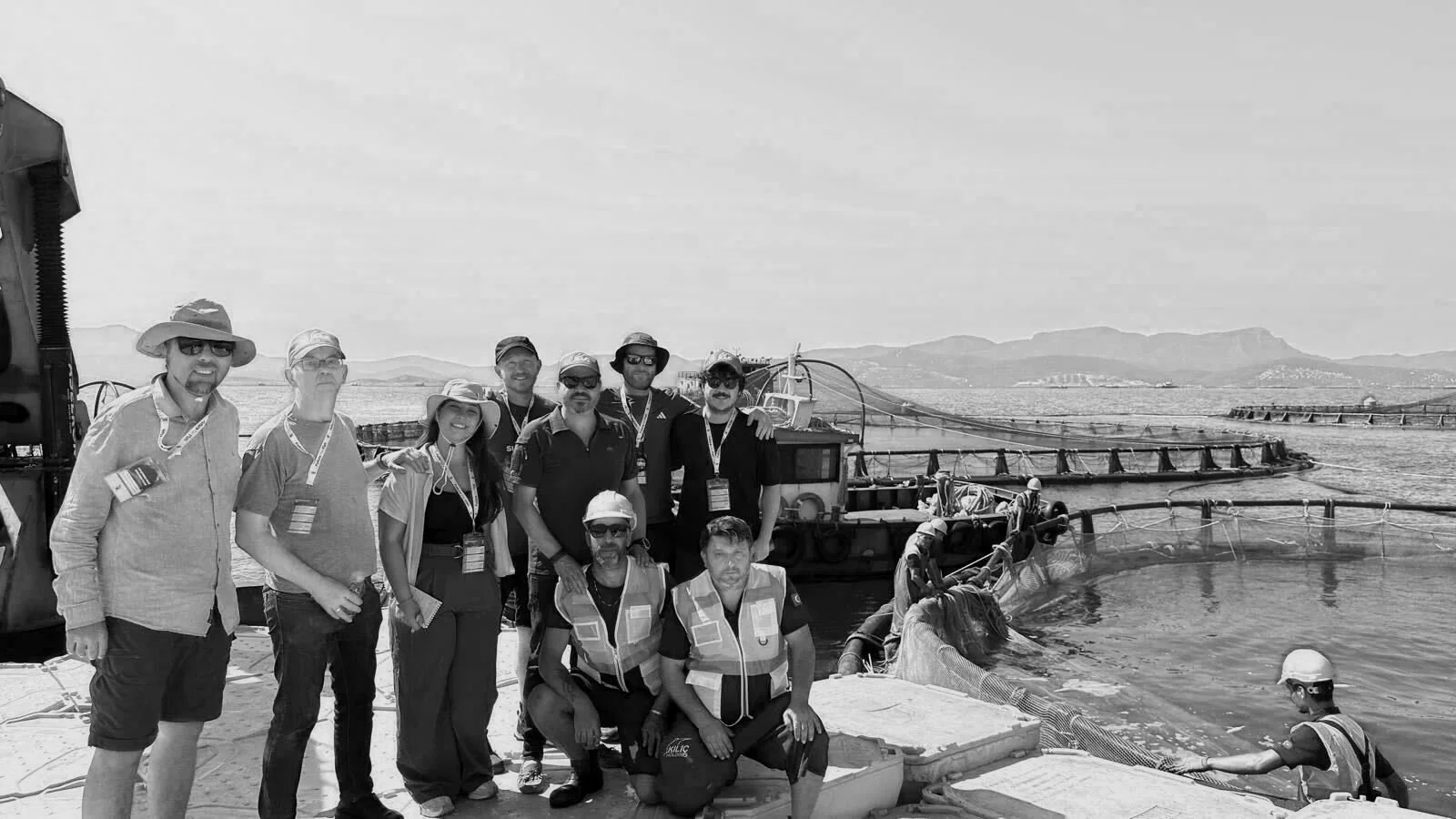 Group of nine people at a dam or water management facility with water and dam structures in the background.