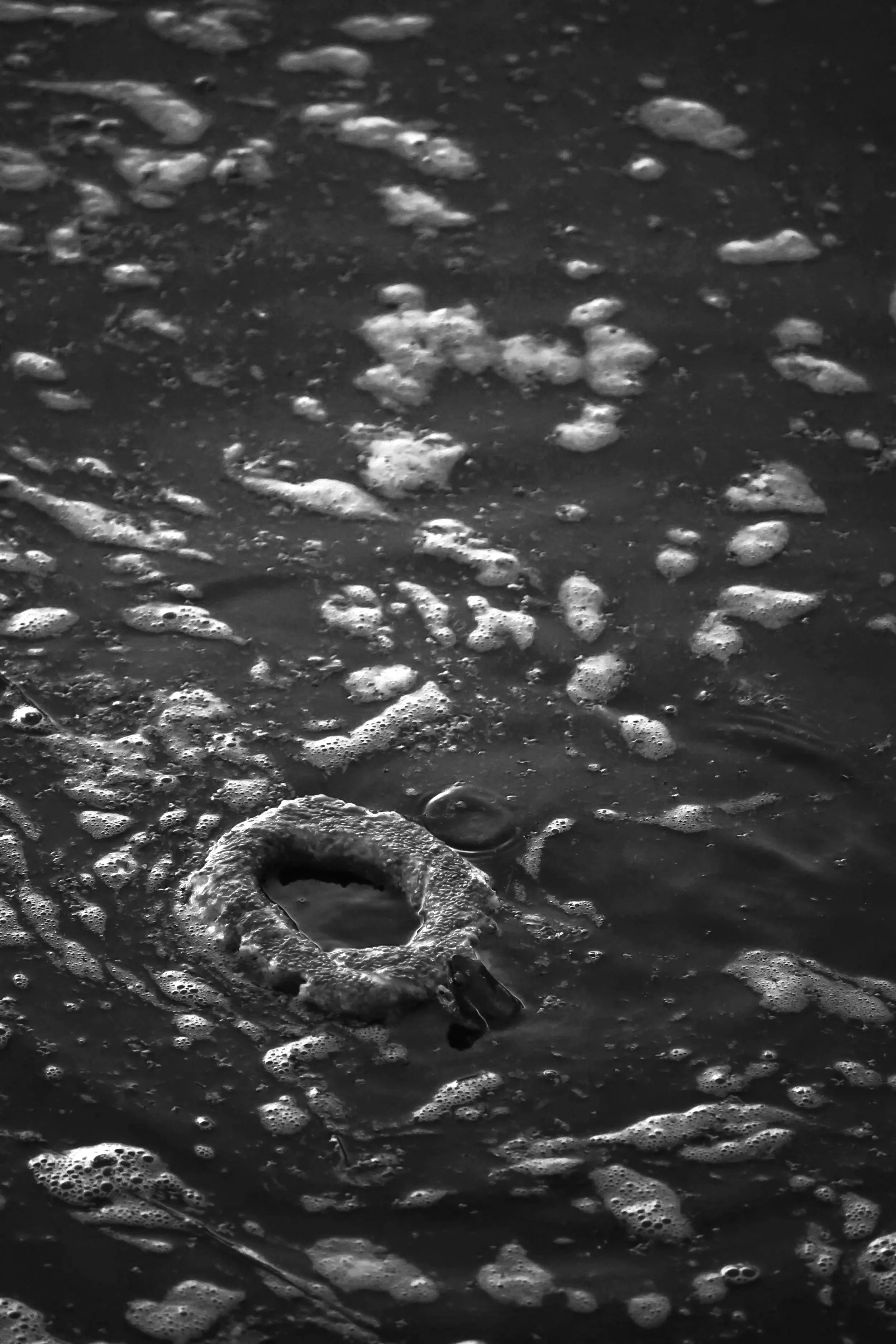 Close-up of foamy ocean waves on the shoreline in black and white.