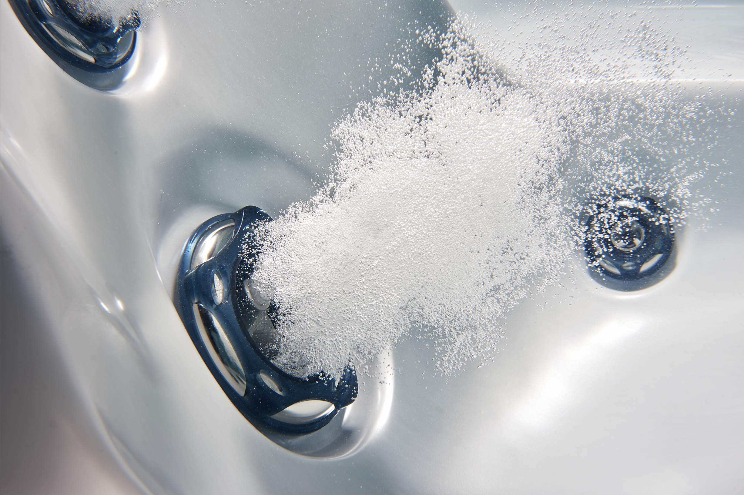 Close-up of a silver sink with water running and bubbles forming around the drain.