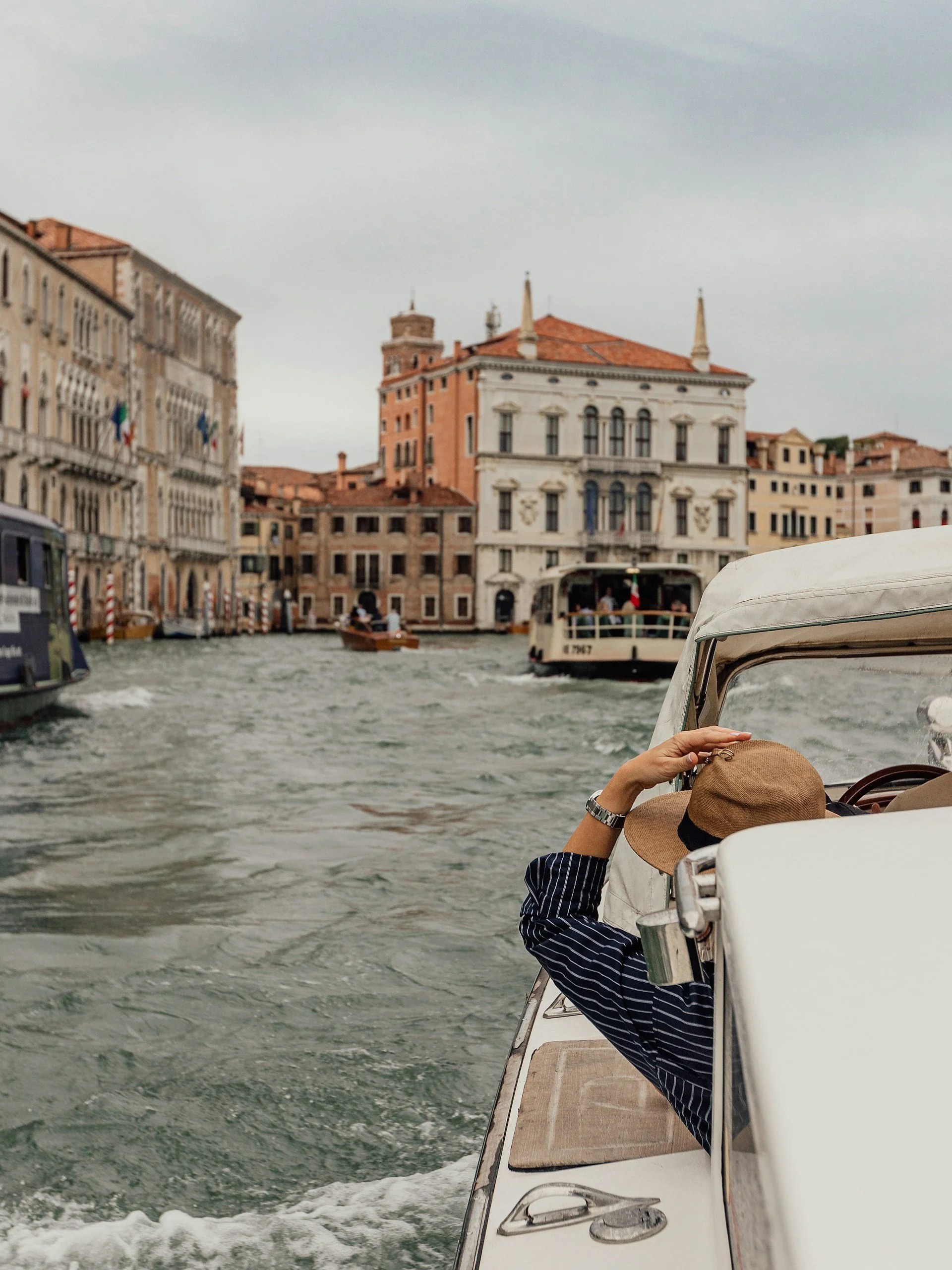 View of a canal in Venice, Italy with boats and historic buildings lining the waterway on a cloudy day.
