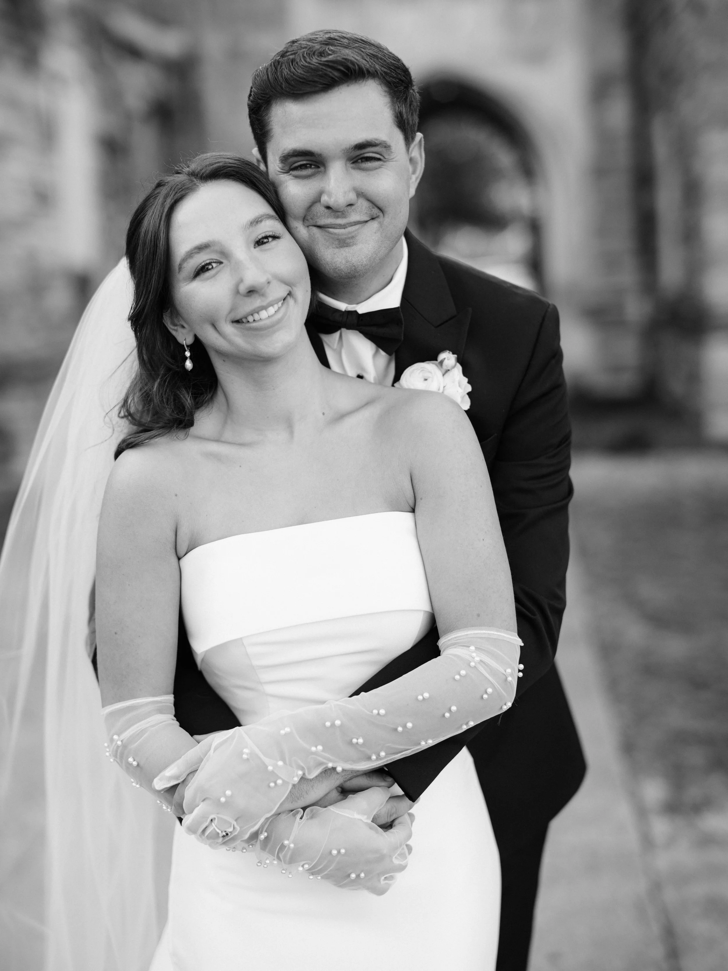 Black and white photo of the company owner and his wife on their wedding day, smiling and embracing outdoors in Middle TN.