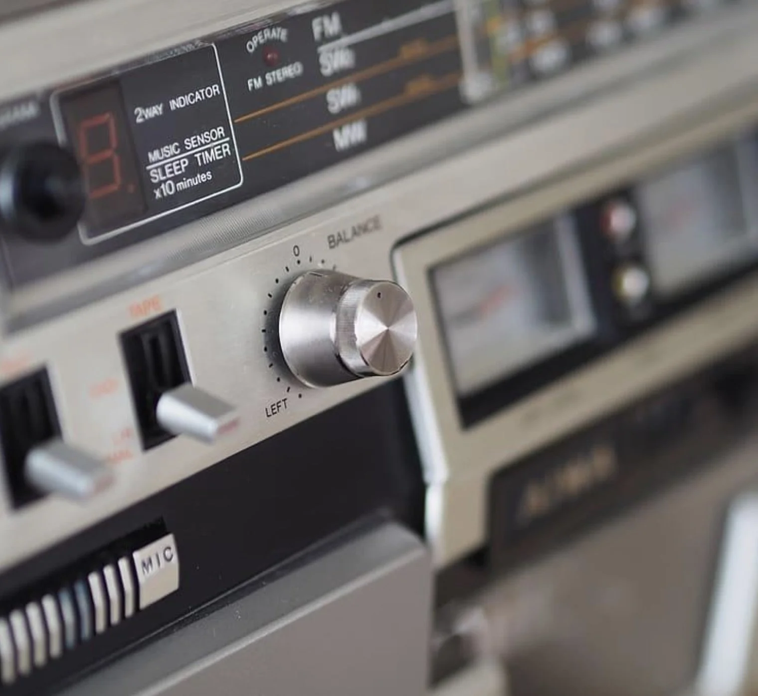 Close-up of a vintage stereo system with knobs, switches, and a digital display.