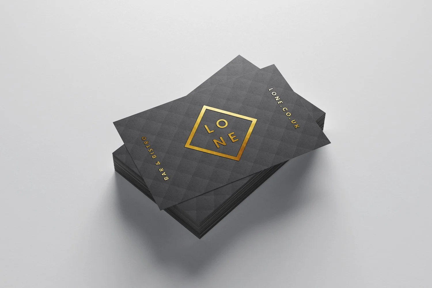 Stack of black business cards with gold foil text and logo for 'LONE,' a bar and bistro in the UK.
