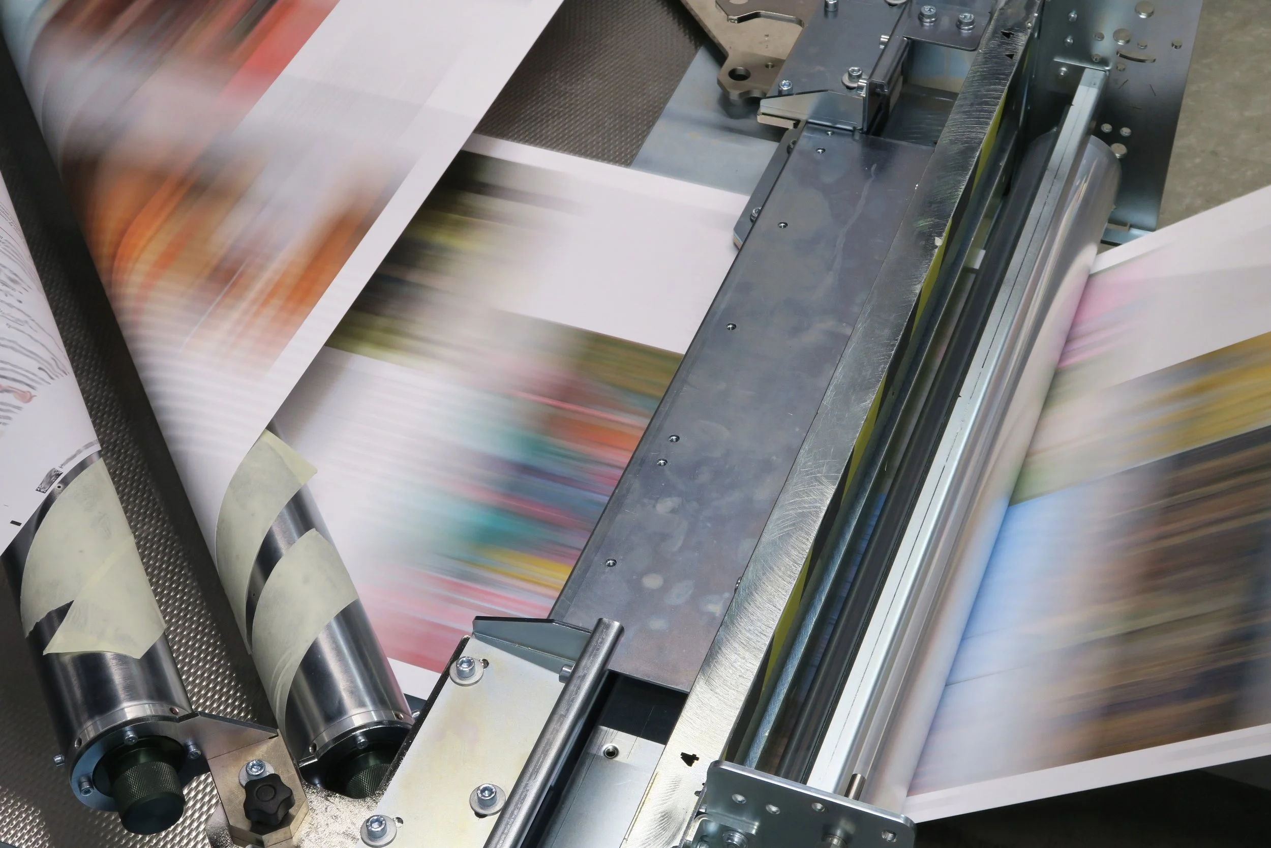 A printing press machine printing a colorful page with blurred motion.