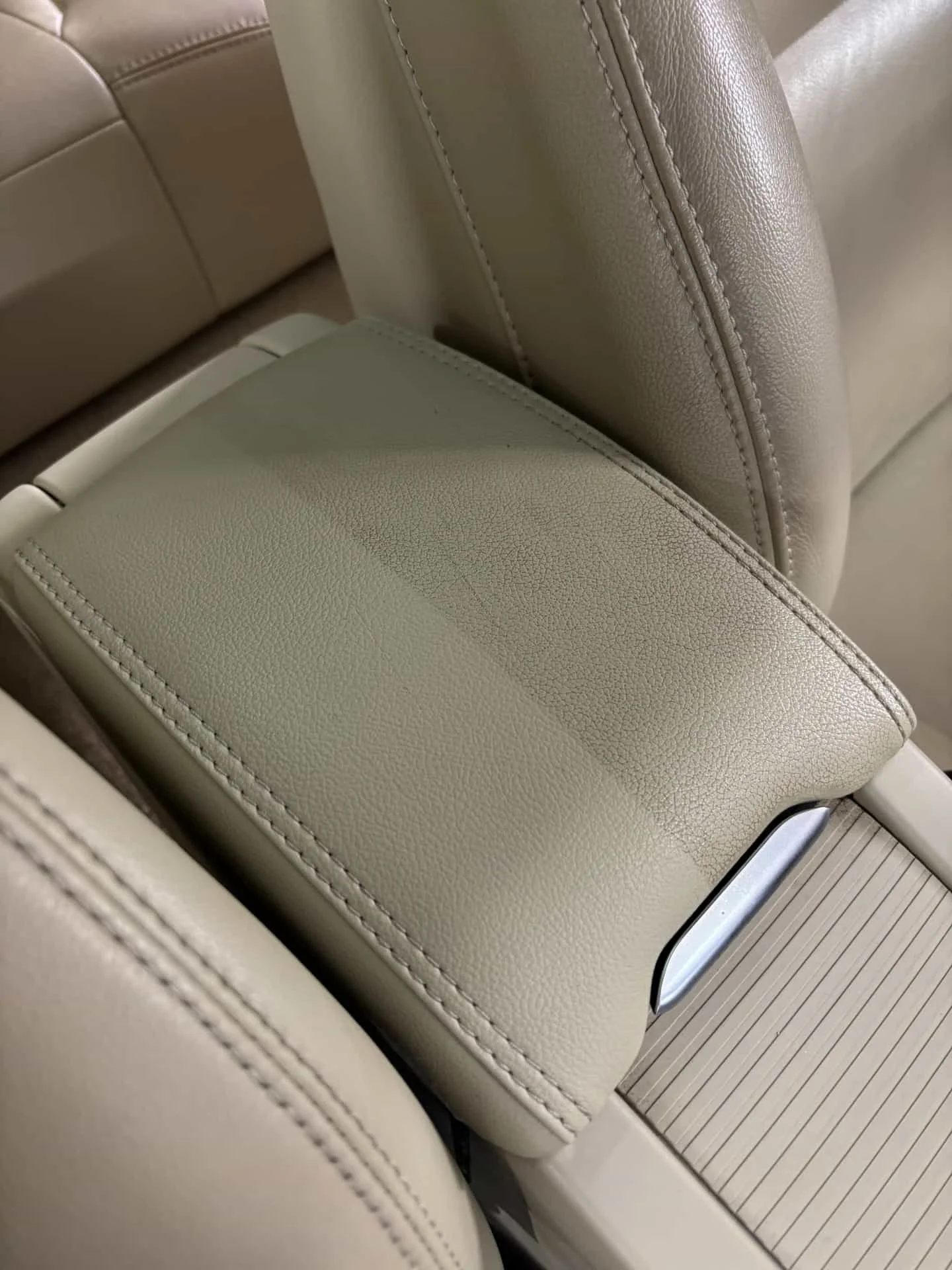 Gros plan d'un siège en cuir beige avec couture visible, dans l'intérieur d'une voiture ou d'un avion.