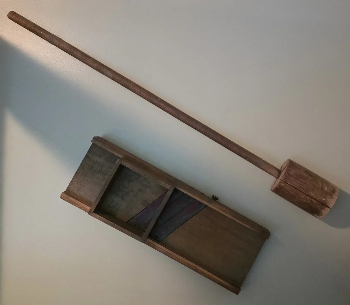 A wooden hammer hanging on a wall.