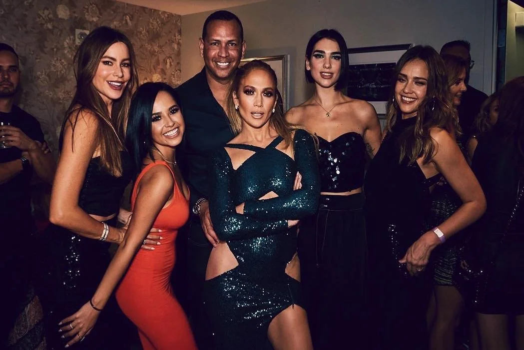 Grupo de personas en una fiesta, vestidos elegantes y sonriendo.