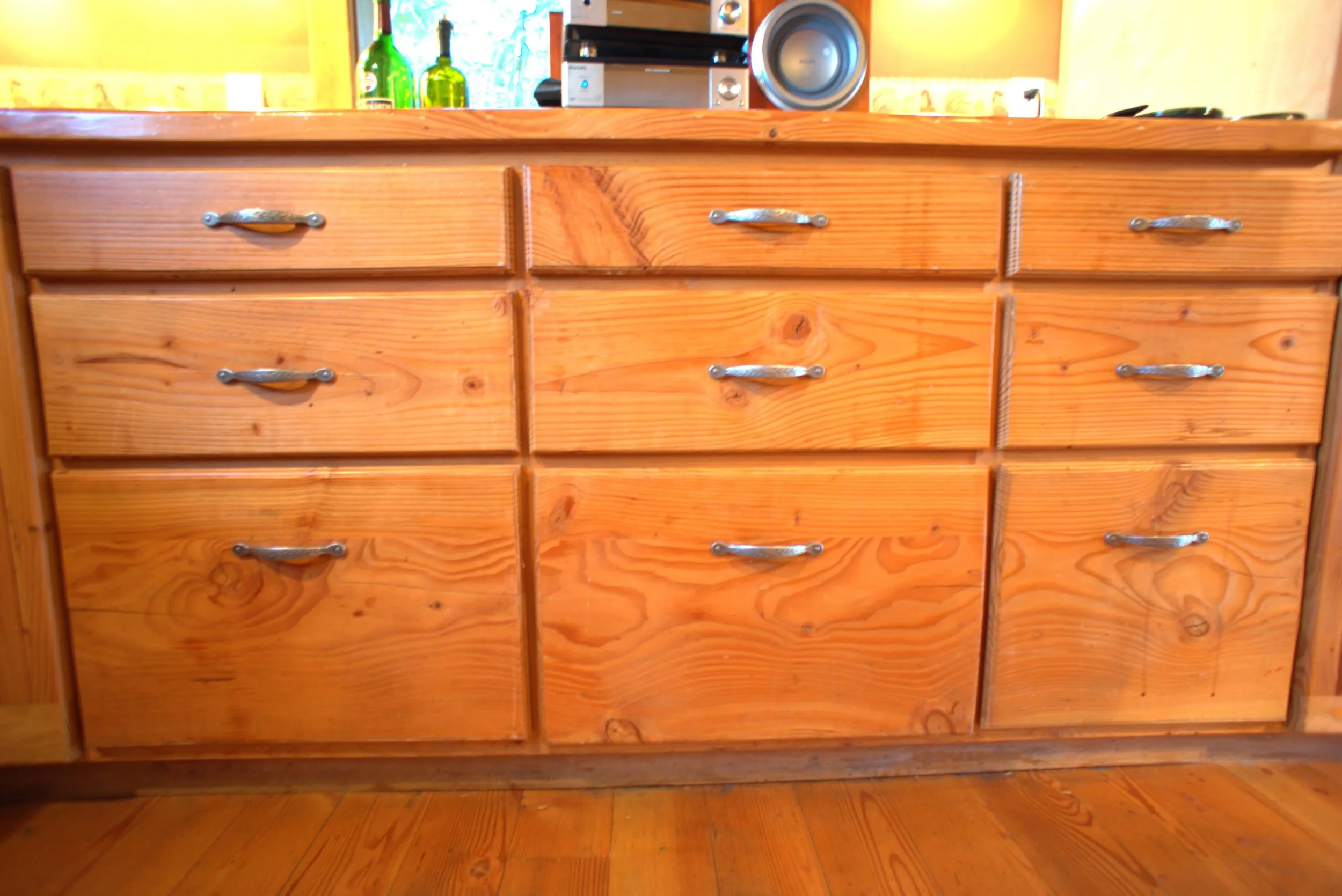 A wooden kitchen cabinet with six drawers, each with metal handles, and a countertop above.