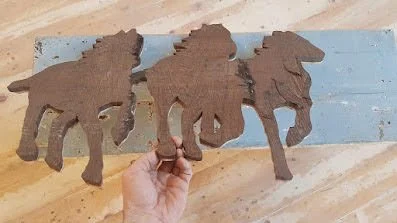 Inlay of three wooden horses before being installed into flooring.