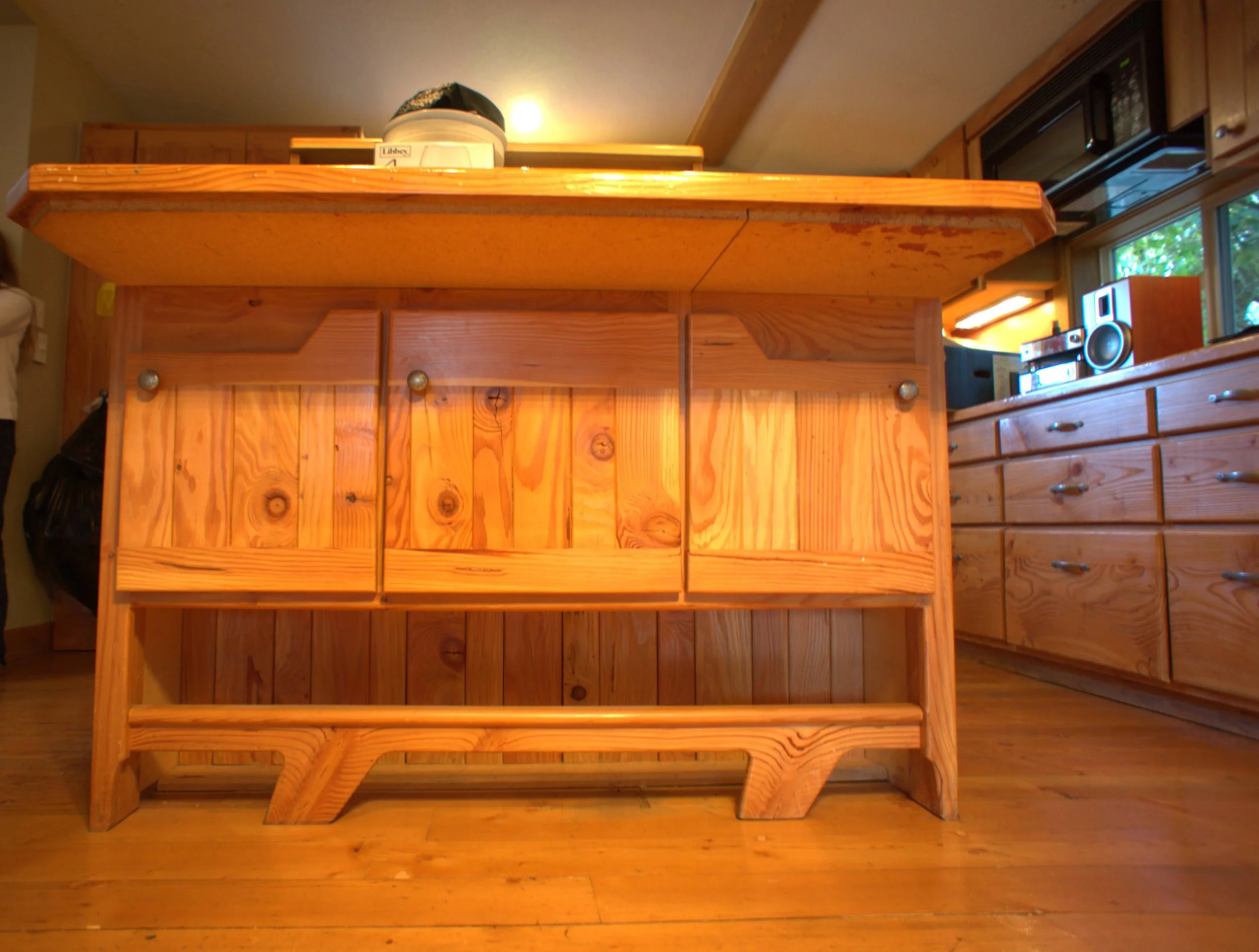 View of a wooden kitchen island with a countertop, with wooden cabinets, and drawers.