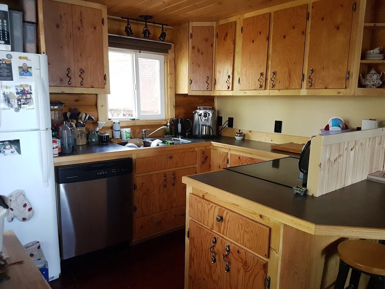 Wooden kitchen with upper and lower cabinets and a small bar area.