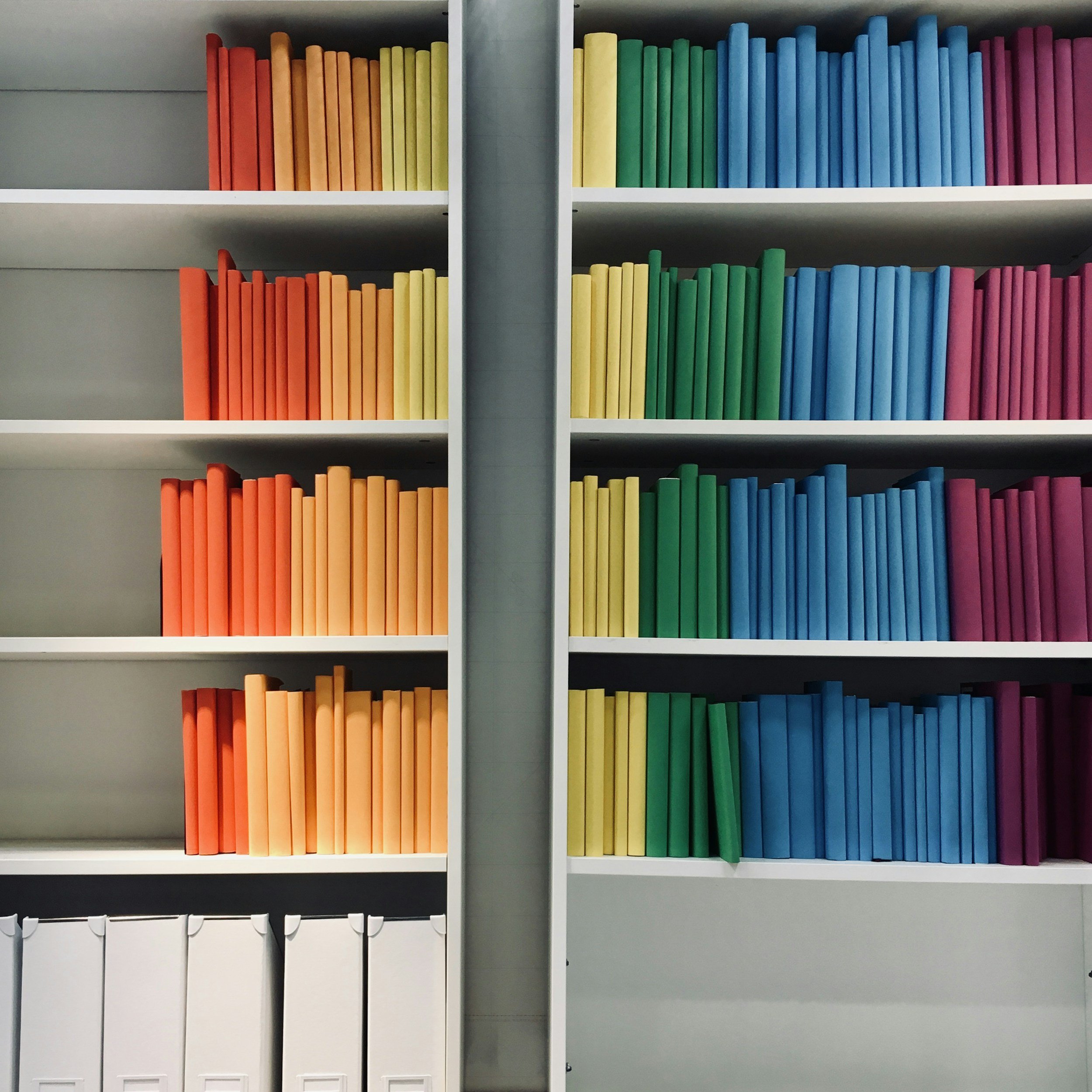 Colorful binders organized on white shelves, files