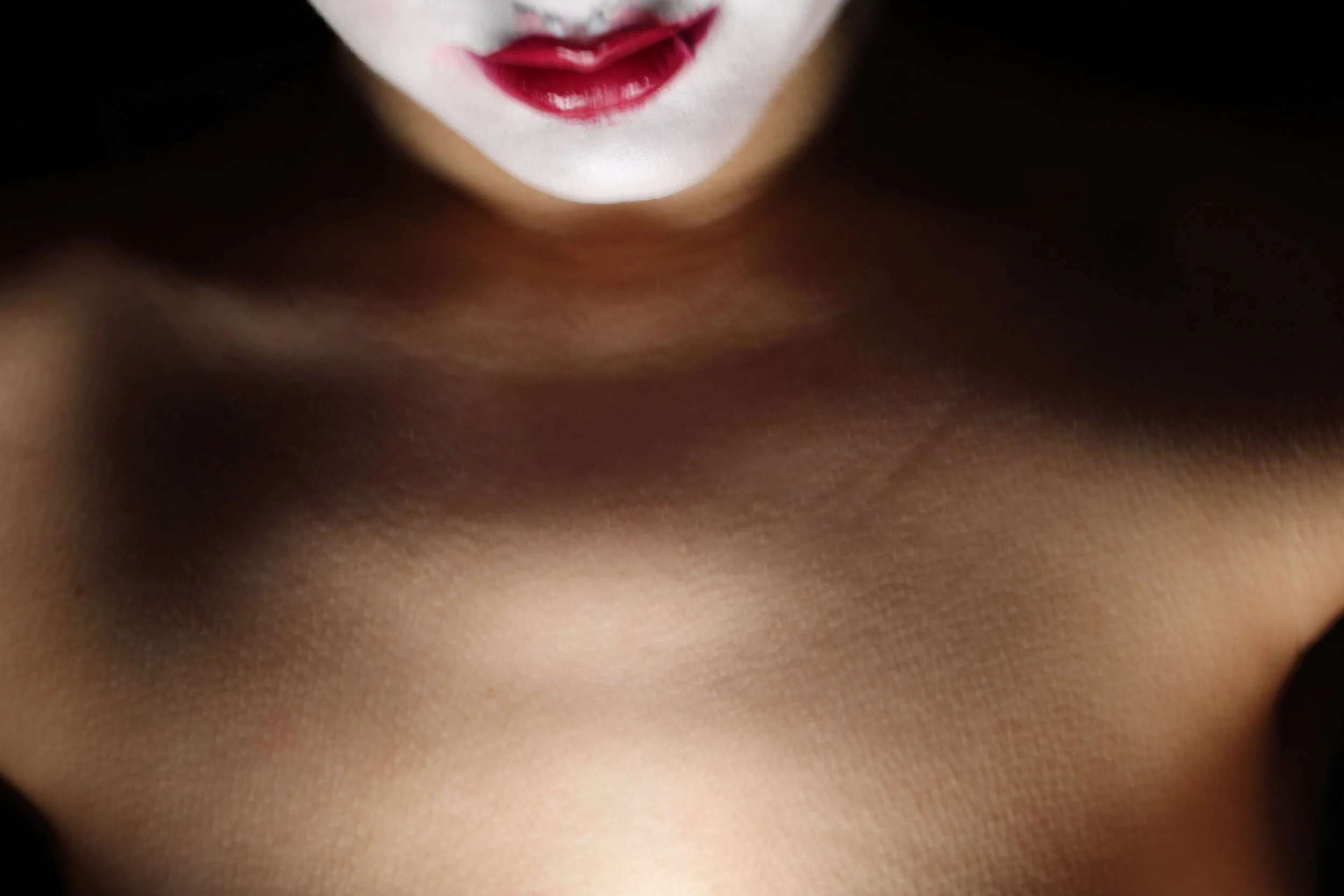 Close-up of a person's lips painted with dark red lipstick, with part of their chin and neck visible.