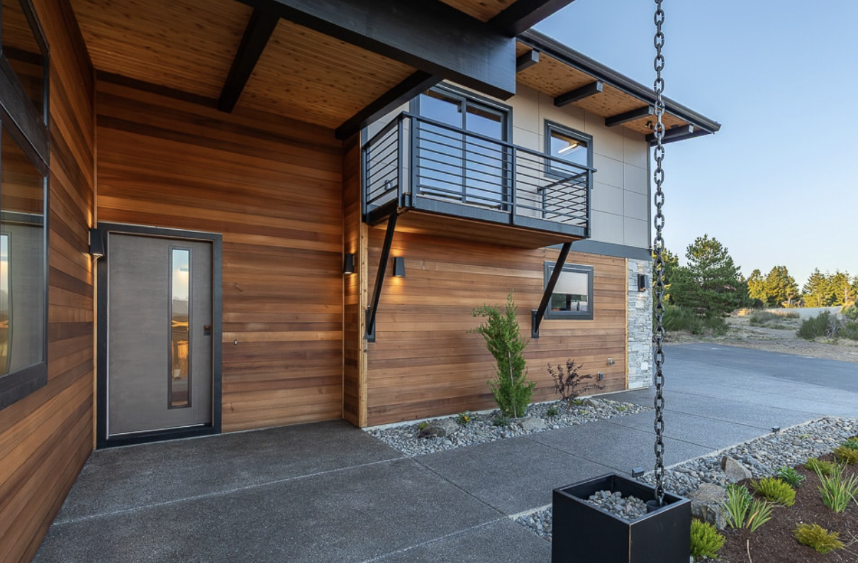 A modern prefab home on the Oregon coast, with vertical wood siding and panelized composite siding.