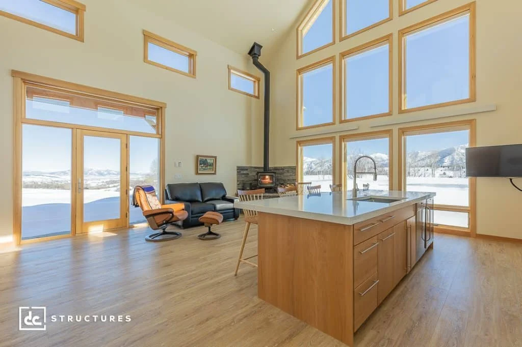 A Scandinavian-inspired ADU with large window walls, wood-trimmed windows, and sleek kitchen features.