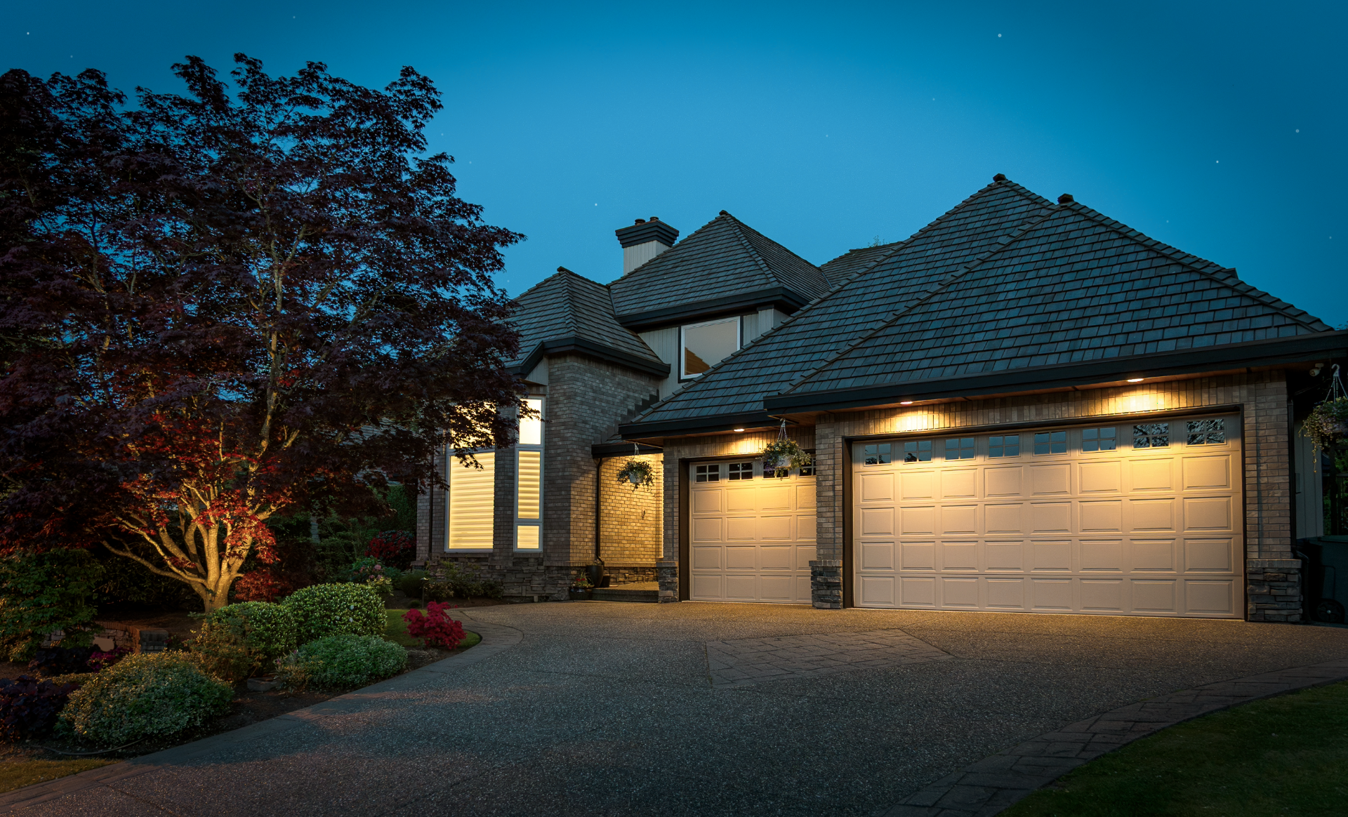 Traditional luxury home exterior at night with warm exterior lighting and landscaping
