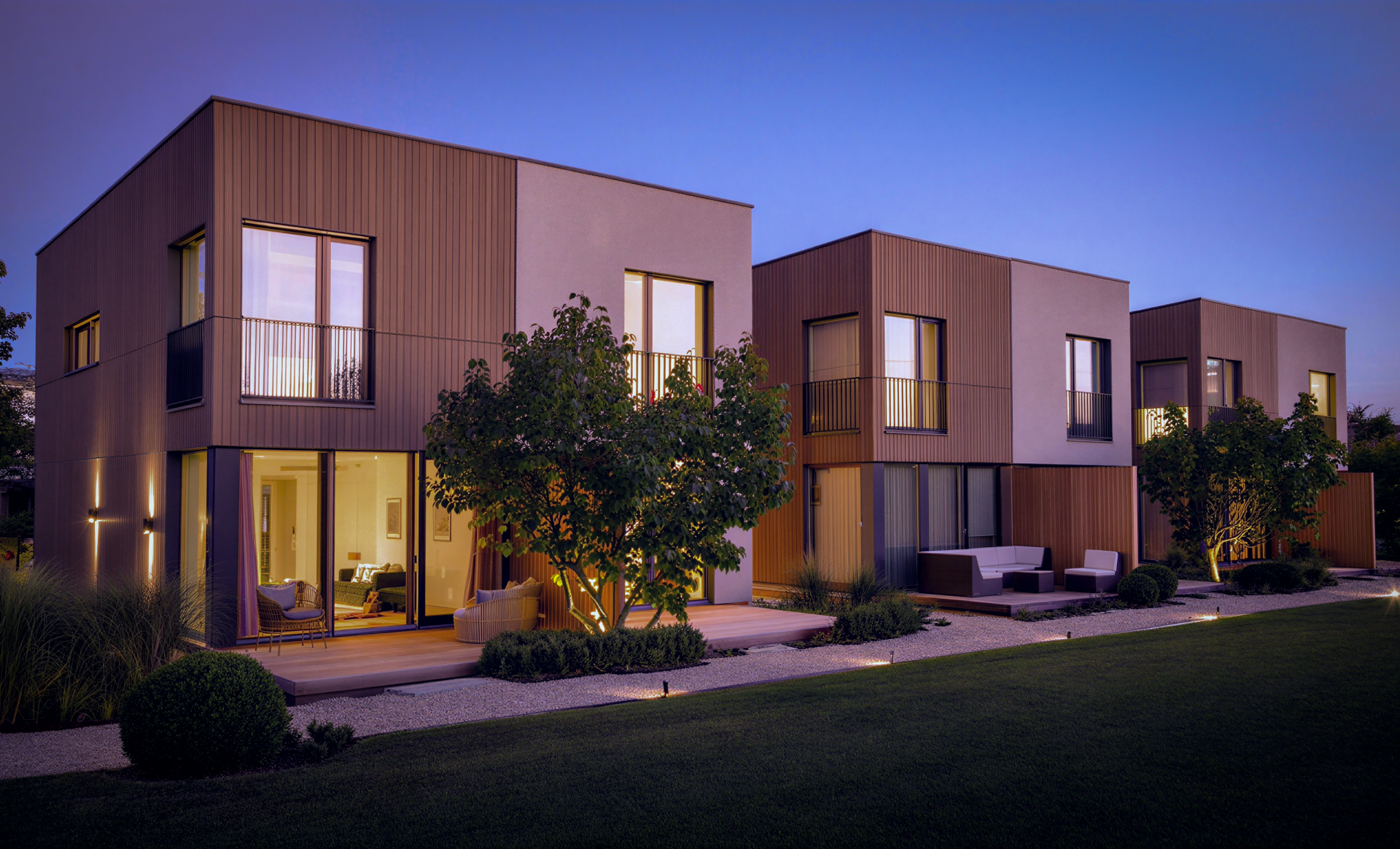 Modern multi-unit residential properties at dusk with warm wood exterior and ambient lighting