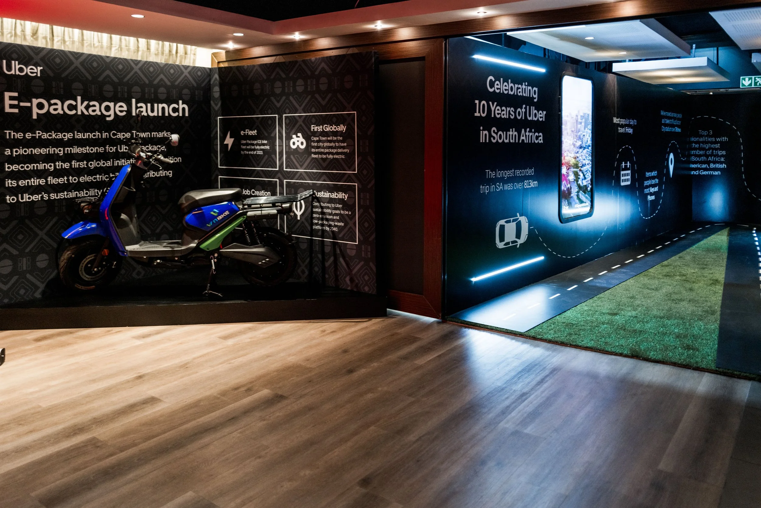 Indoor exhibit celebrating Uber's 10 years in South Africa, featuring a blue electric scooter and informational displays about electric bikes and Uber's sustainability initiatives.