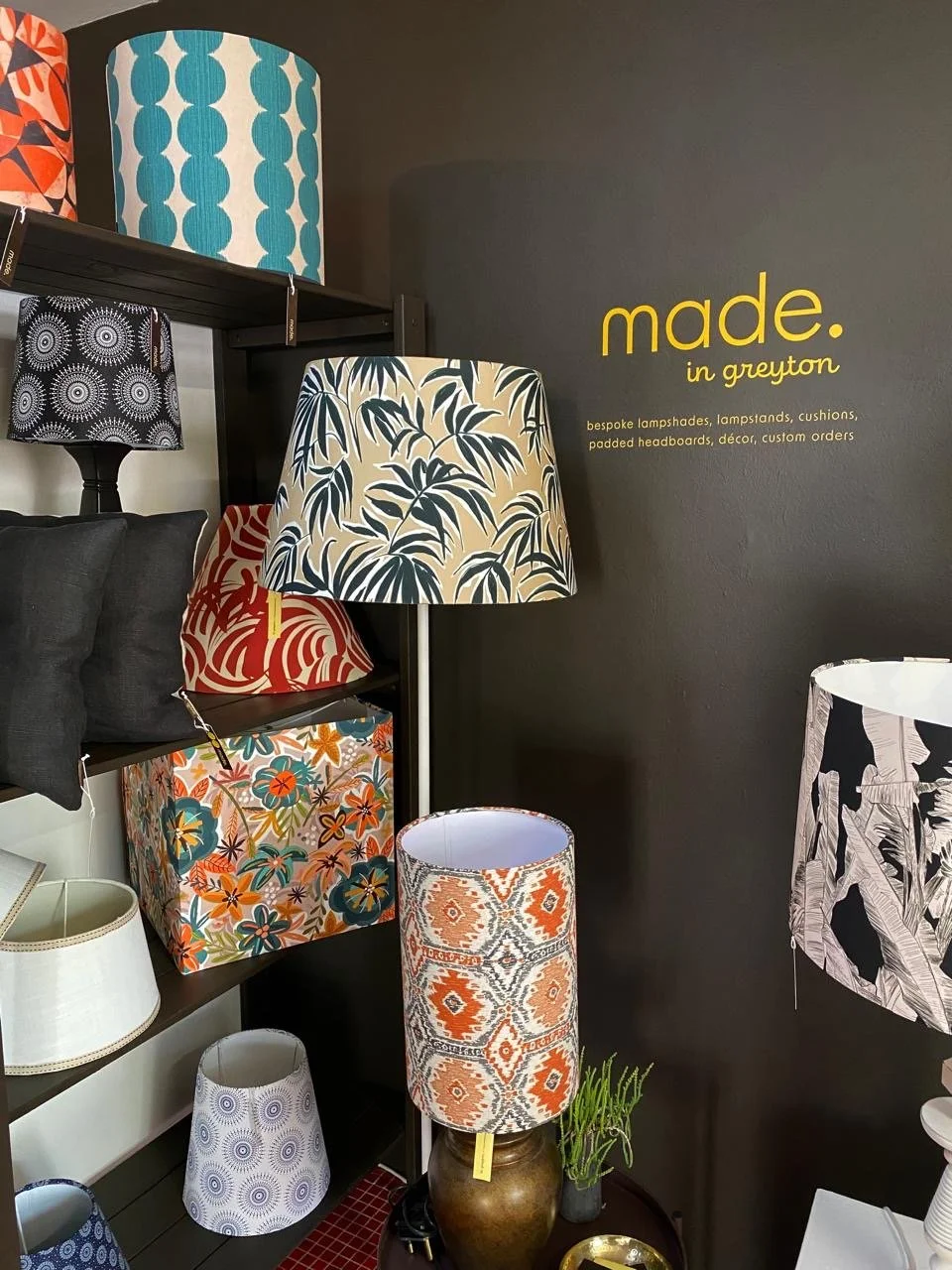 Display of various decorative lampshades with different patterns and colors in a store. I designed the logo vinyl signage for the inside of the store.