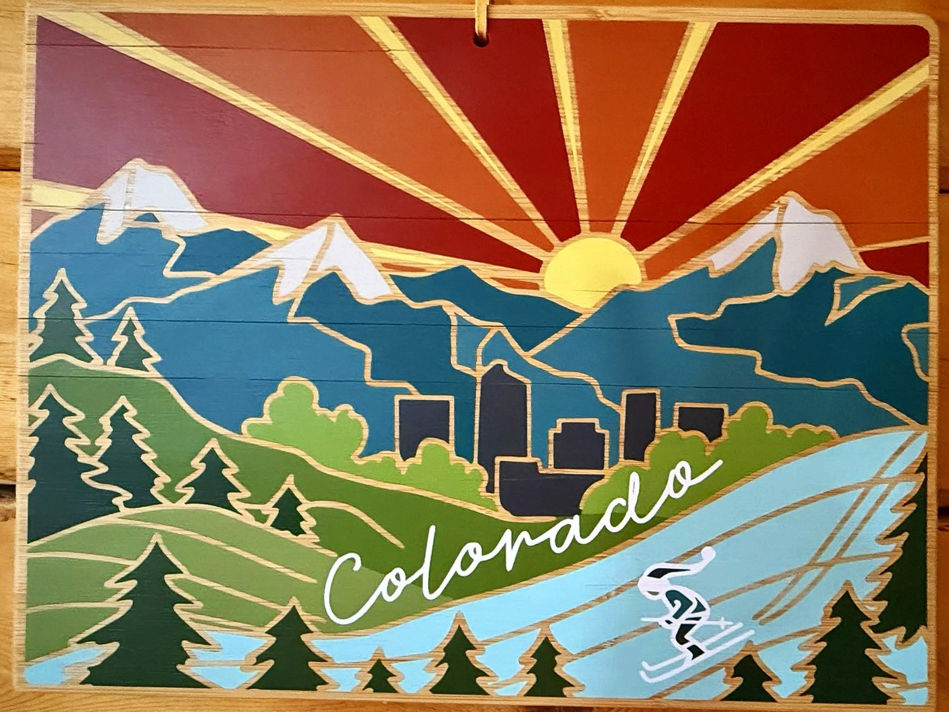 Illustration of a mountain range with a sun rising behind the peaks, a cityscape in the foreground, evergreen trees, and a river flowing through the scene, with the words "Colombia" and "c" partially visible.