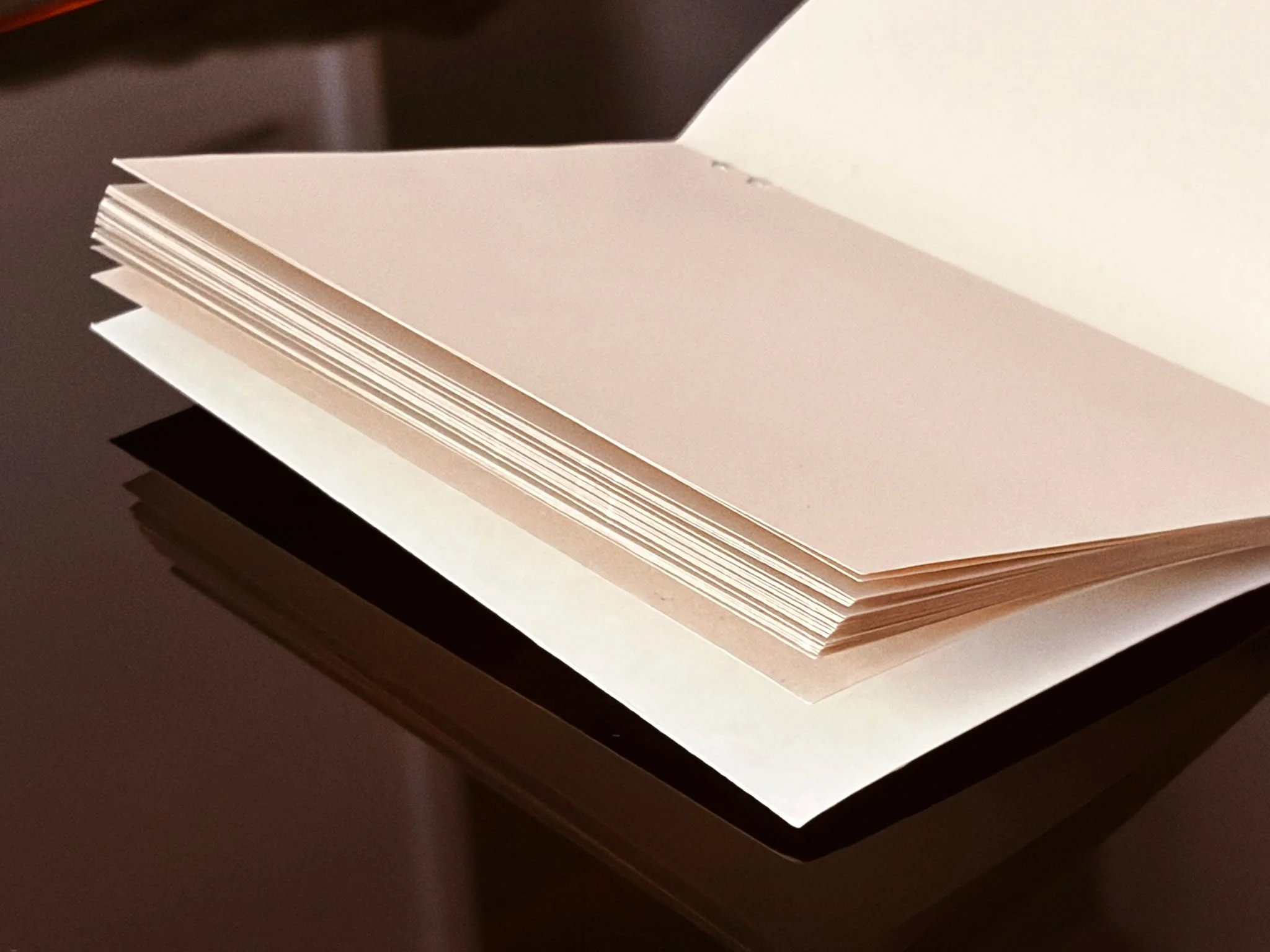 Close-up view of a blank white sheet of paper resting on top of a thicker paper or cardboard surface.