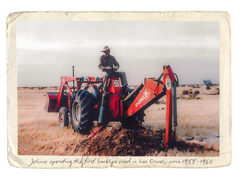 A person operating a vintage red tractor with a front loader in an open field, with a handwritten caption at the bottom reading, "Johnny operating the first backhoe used in Las Cruces, circa 1957-1960."