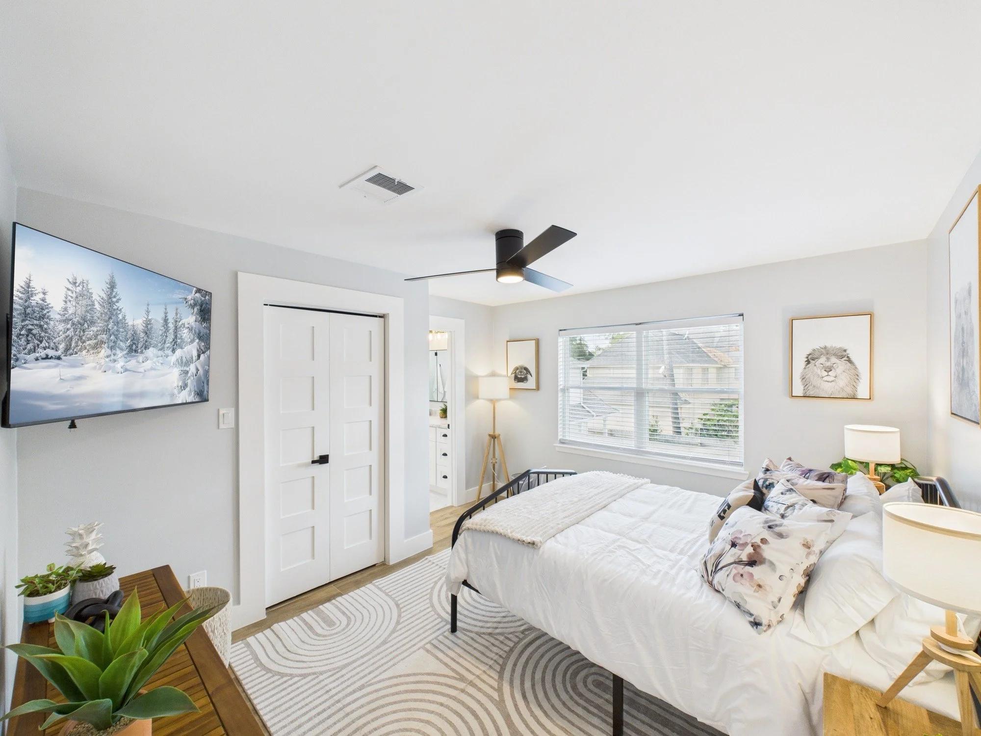 A bedroom with a bed, pillows, a nightstand, and wall art featuring animals, including a lion and a panda, with a window showing an outdoor scene.