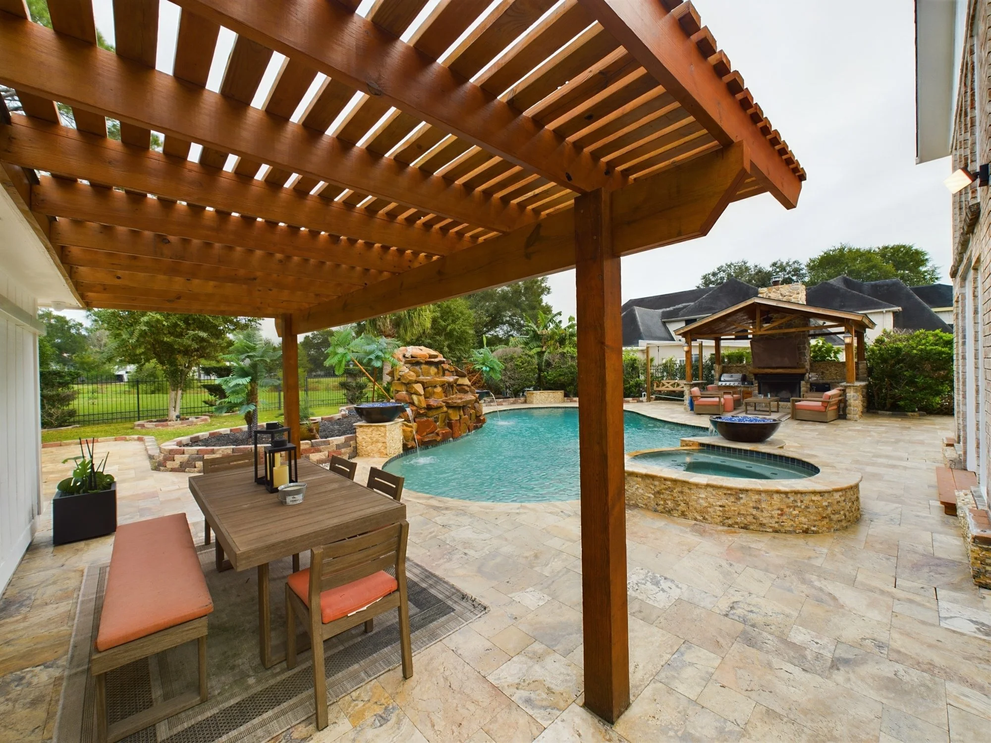 Backyard patio with wooden pergola, swimming pool, outdoor seating area, and landscaped yard with trees.