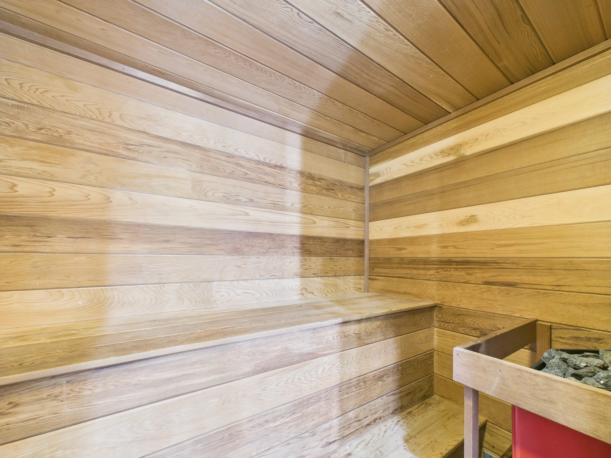 Wood-paneled corner room with a wooden planter in the bottom right corner containing rocks.