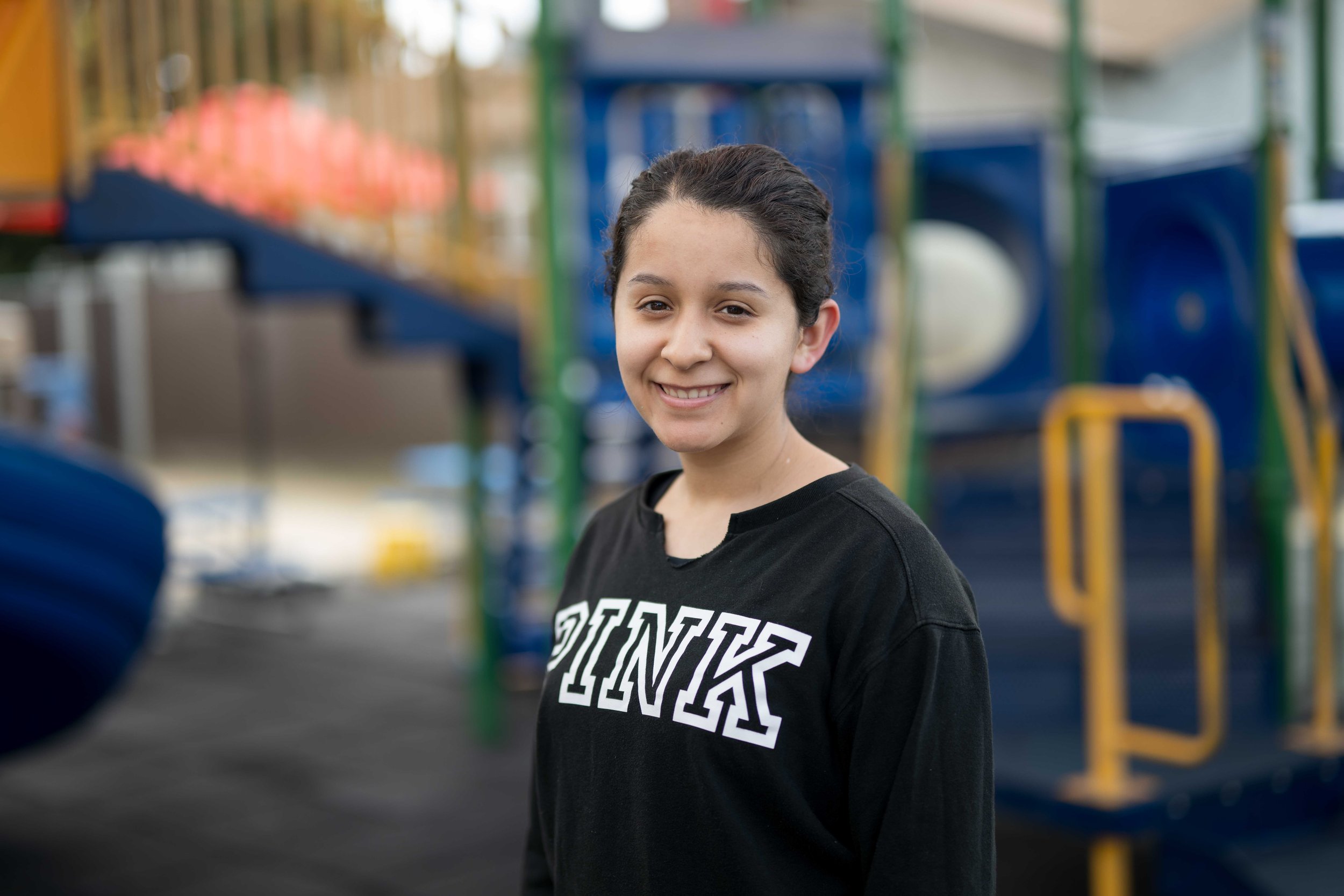 A young girl smiling at the camera at a playground.