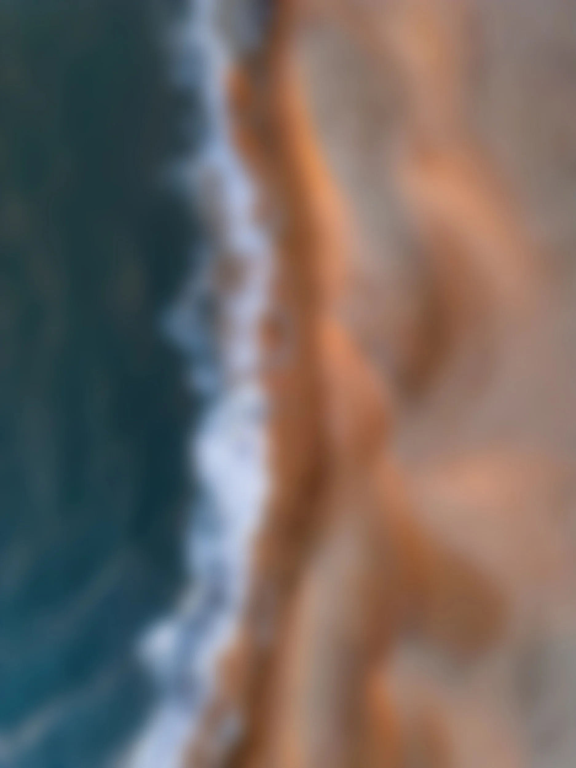 A blurry abstract close-up of a person's hand holding a pen or pencil, with natural light illuminating the scene.