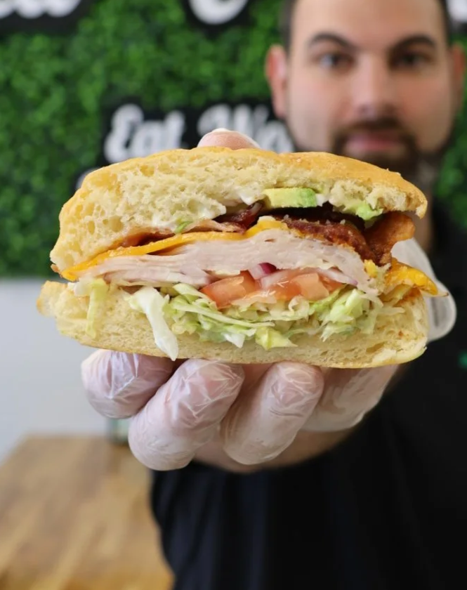 Karim Karkar owner of Stacked and Tossed holding a fresh stacked sandwich in Shreveport Bossier Louisiana
