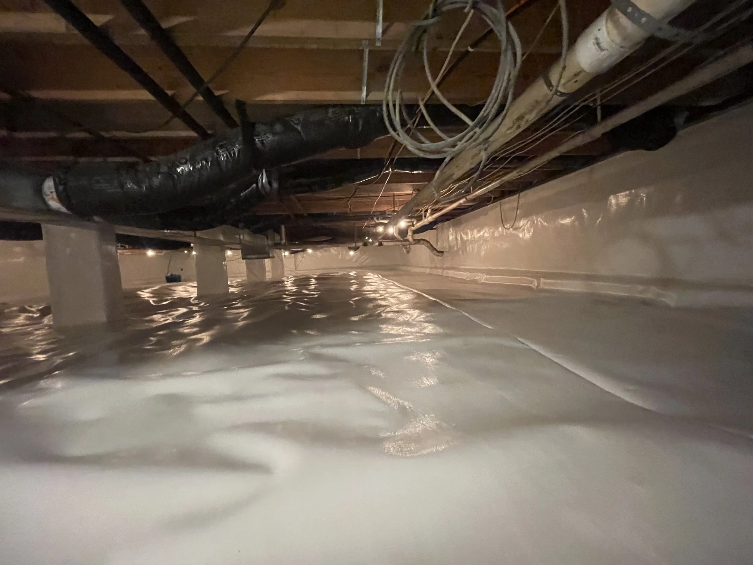 Crawl space encapsulation with vapor barrier installed to control moisture and protect the home.