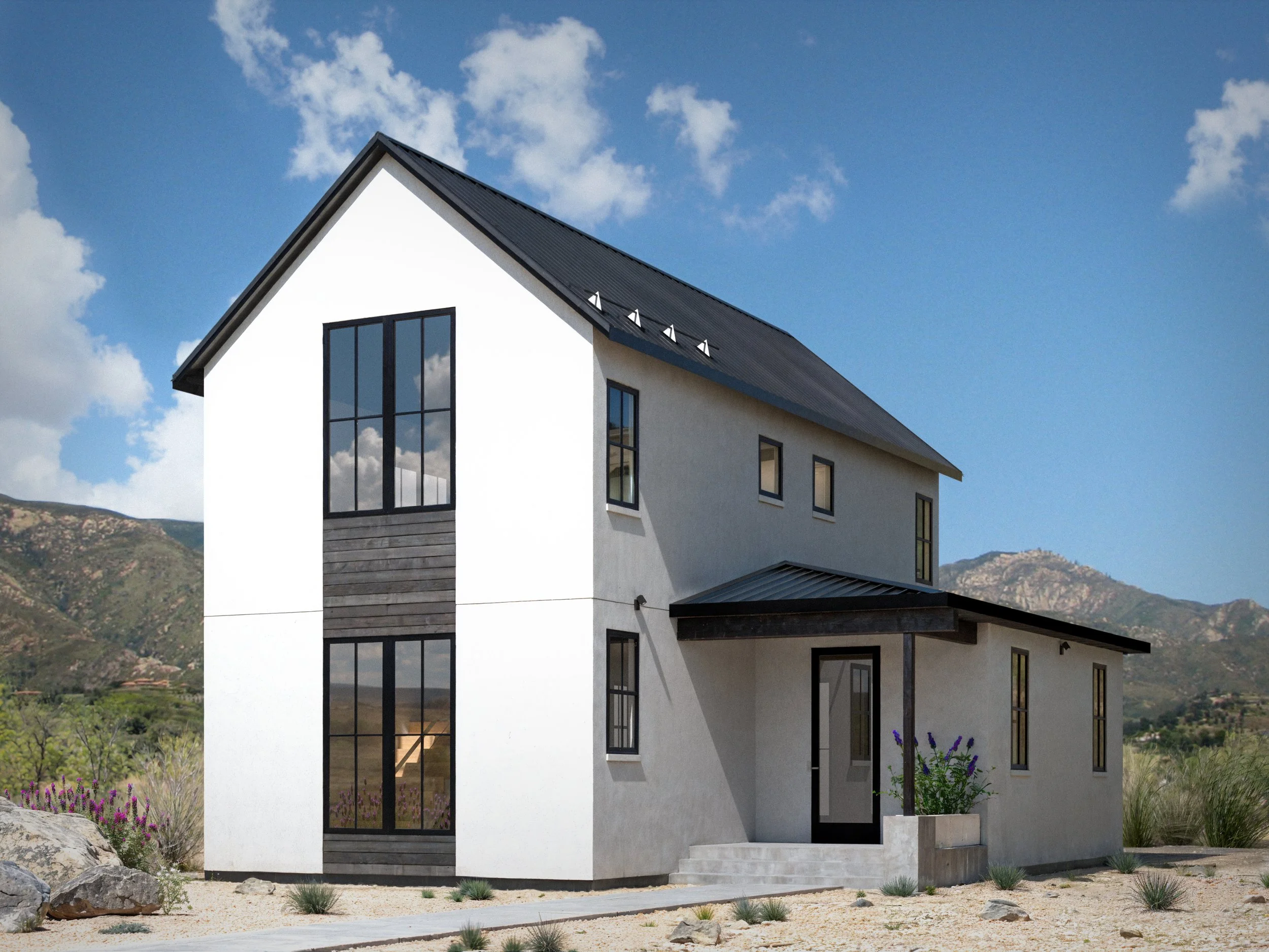 Modern white house with large black-framed windows, a black metal roof, and a small staircase leading to the entrance, set against a background of mountains and partly cloudy sky.