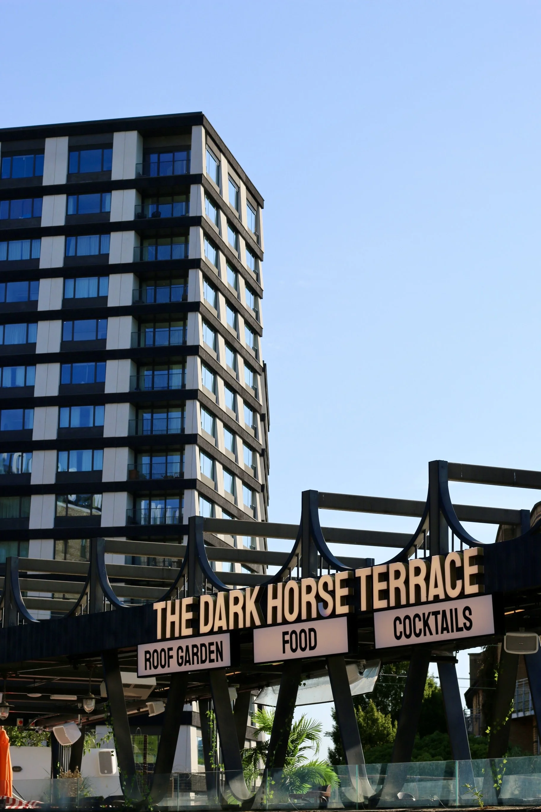 Schild zeigt Food, Cocktails, Roof Garden, Open, The Dark Horse Terrace