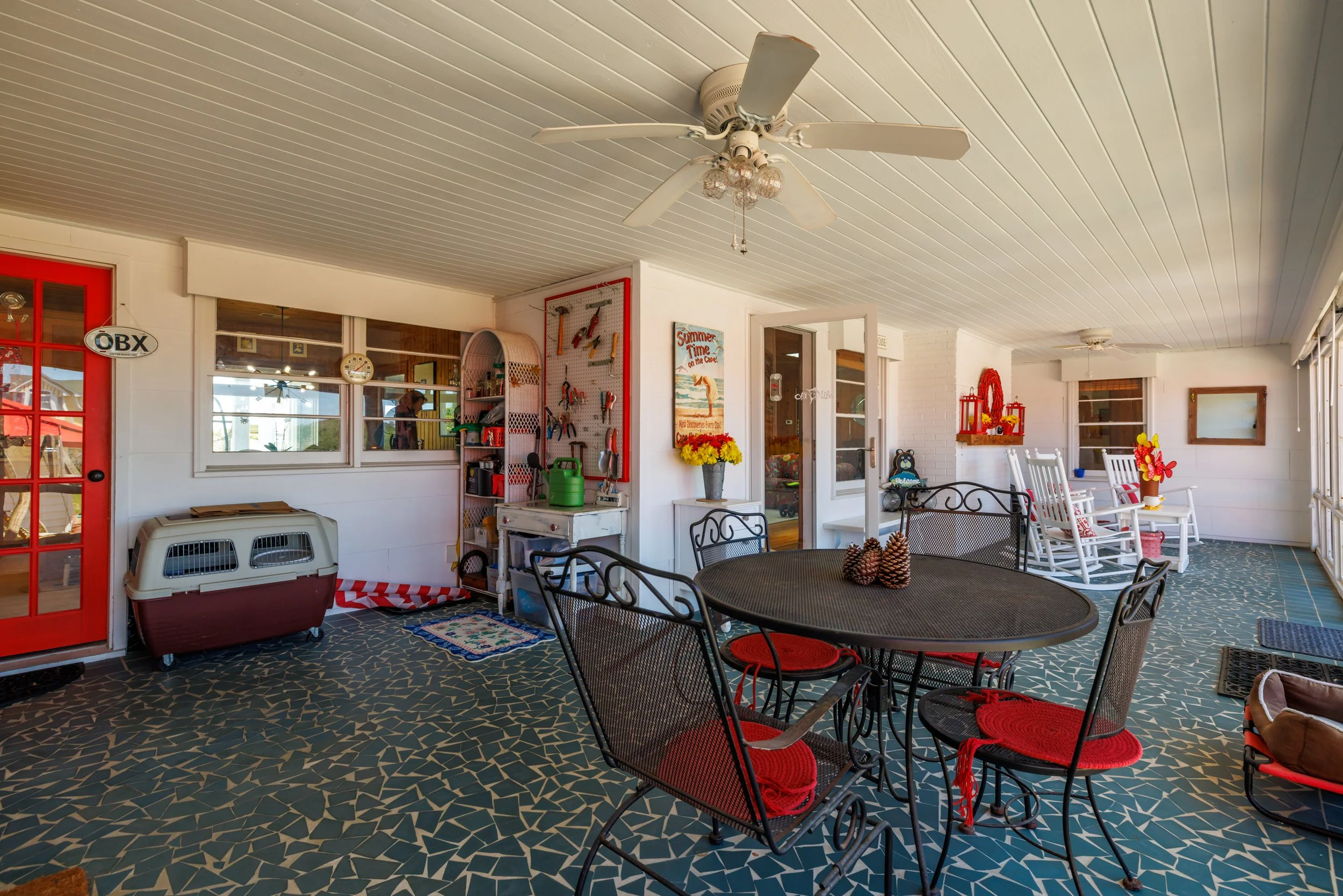 Covered porch area with outdoor furniture, a ceiling fan, and gardening tools on a pegboard.