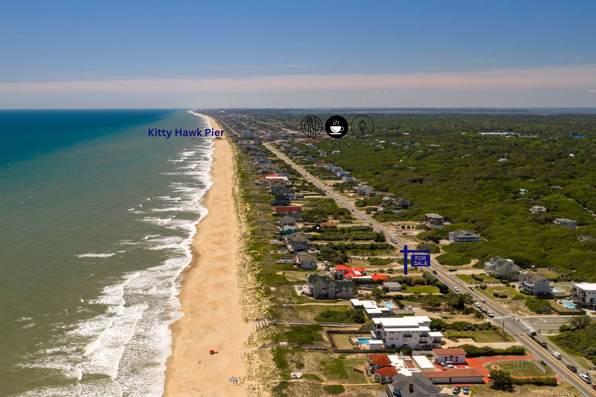 Aerial view of Kitty Hawk Pier and beach in North Carolina, showing ocean, sandy shoreline, and homes along the coast. Overlay icons include a fork and knife, a coffee cup, and an ice cream cone, with a for sale sign near the road.