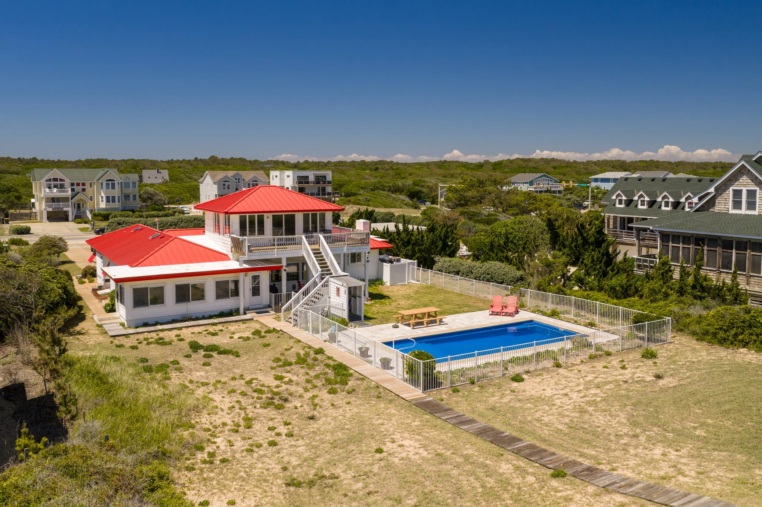 View of a coastal neighborhood with houses, a swimming pool, and a clear blue sky.