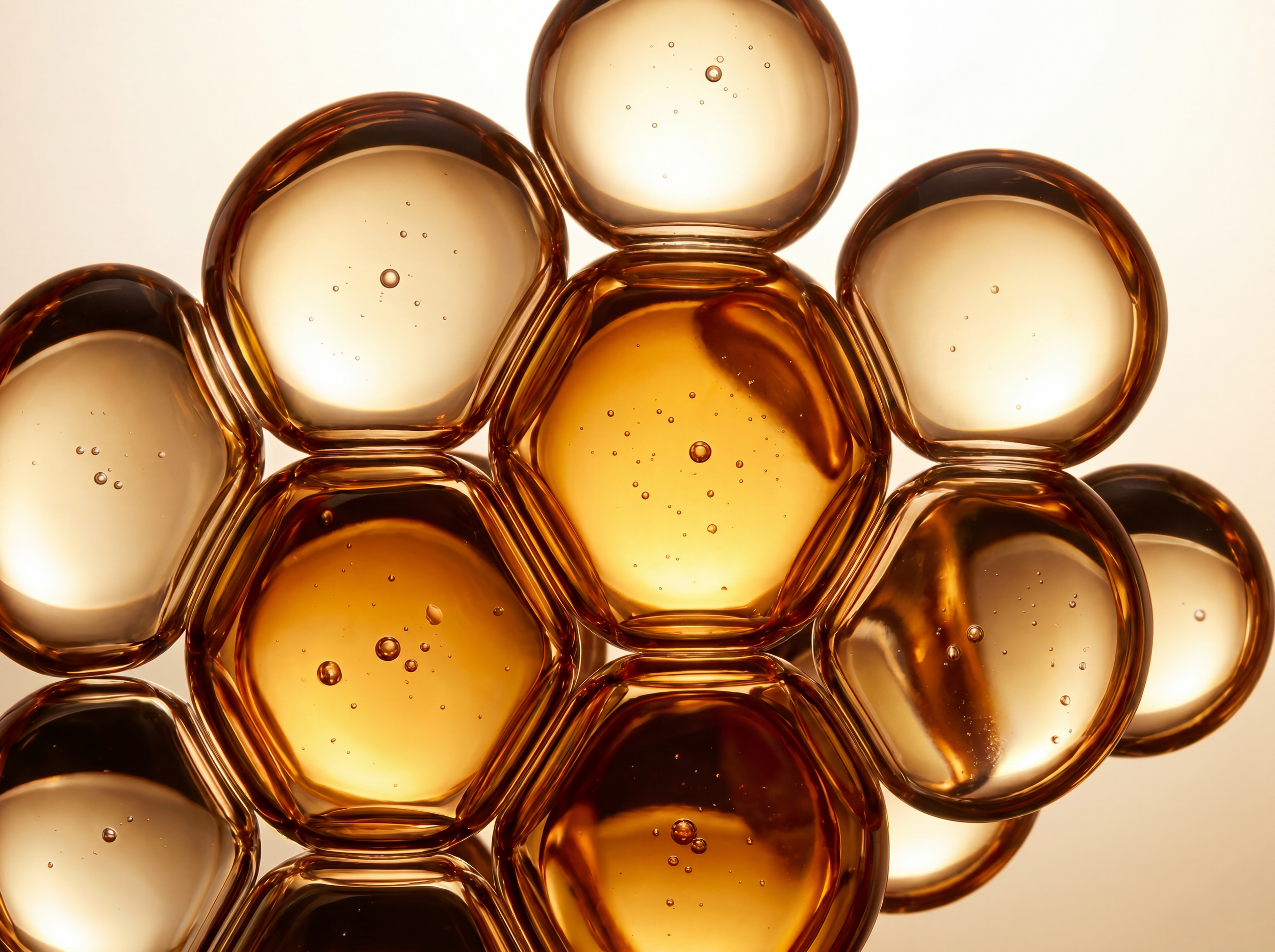 Close-up of several honey-colored, translucent glass marbles with bubbles inside, clustered together on a light background.
